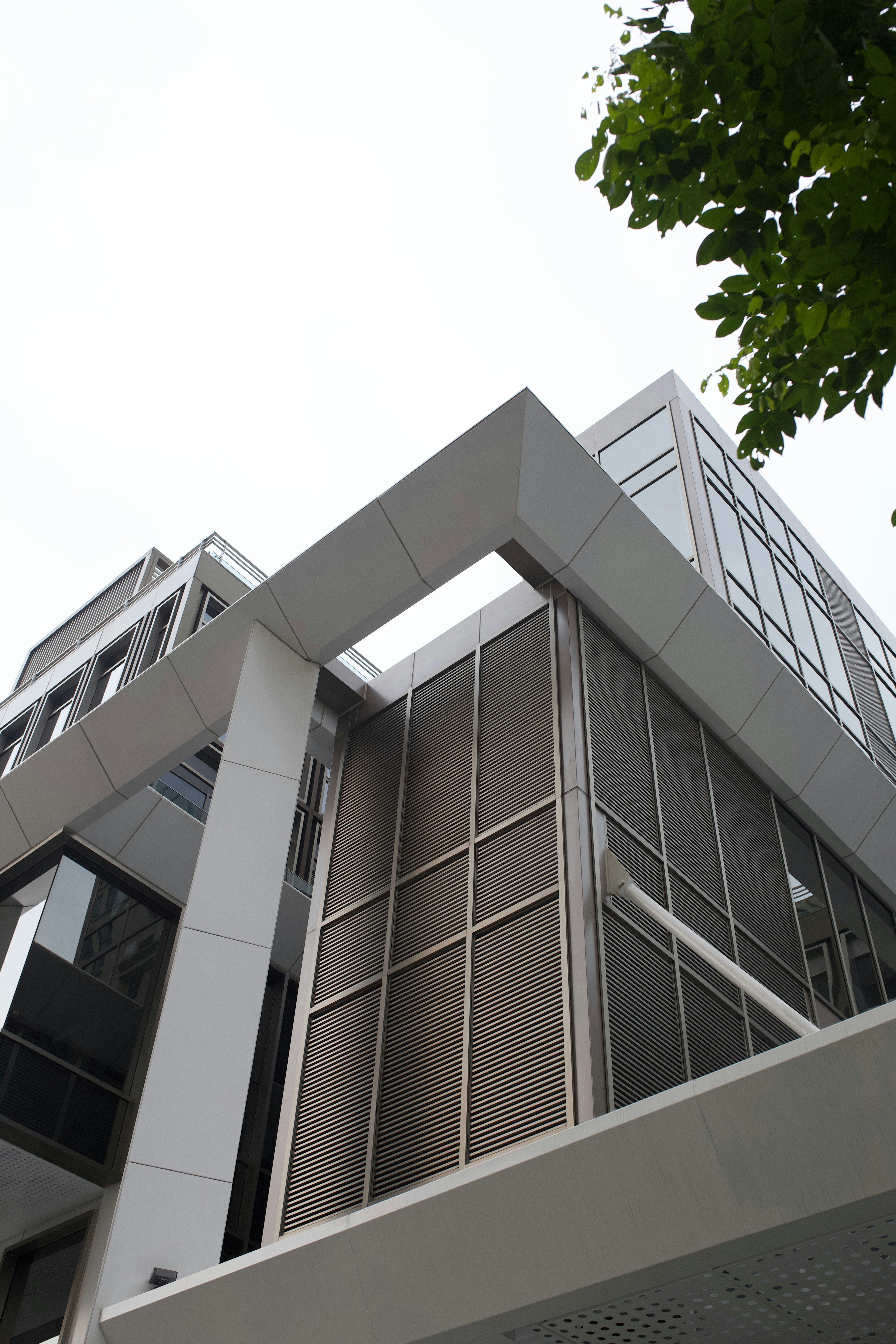 A modern building with glass windows and metal louvers under a bright ...