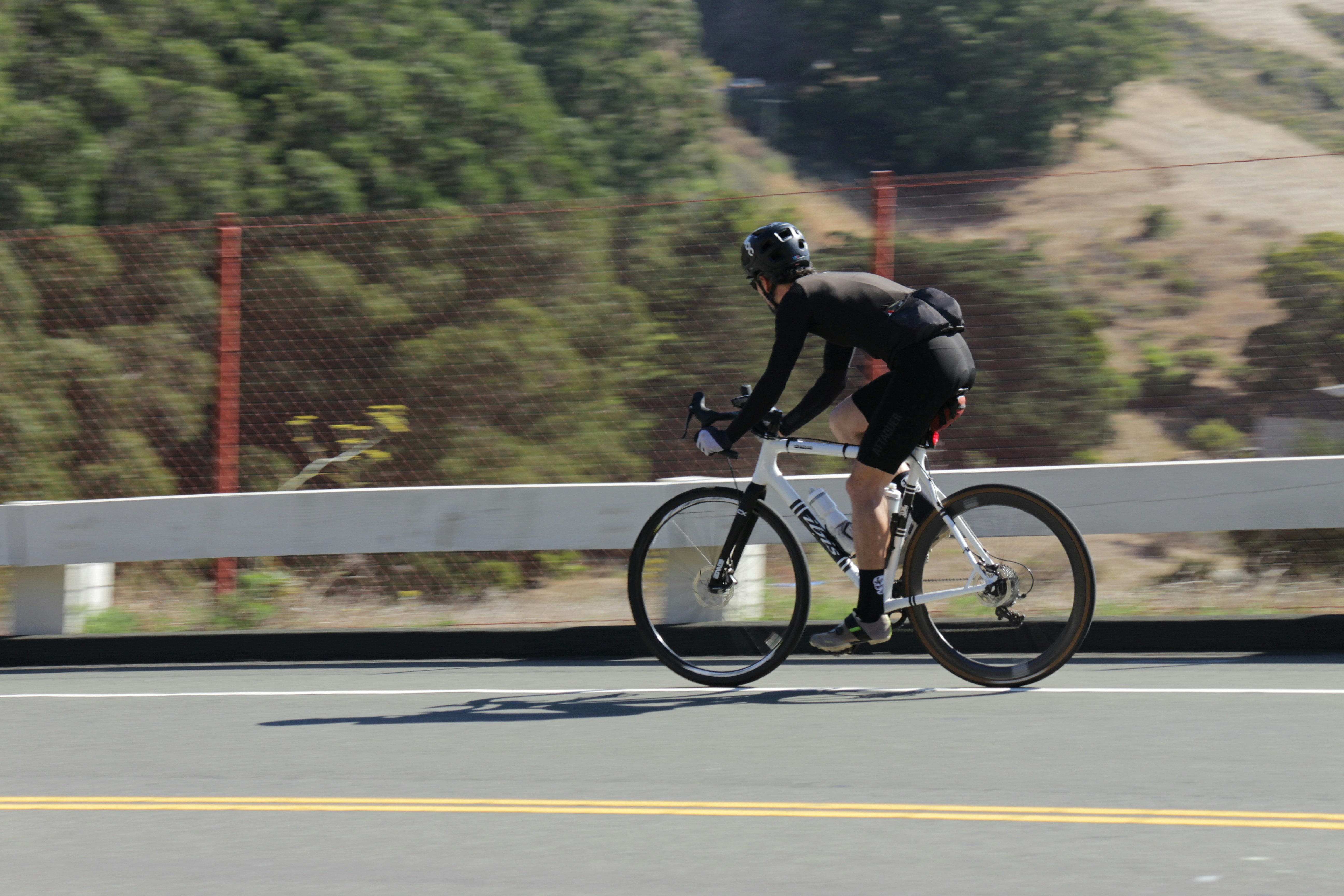 A cyclist rides a white bicycle on a road.