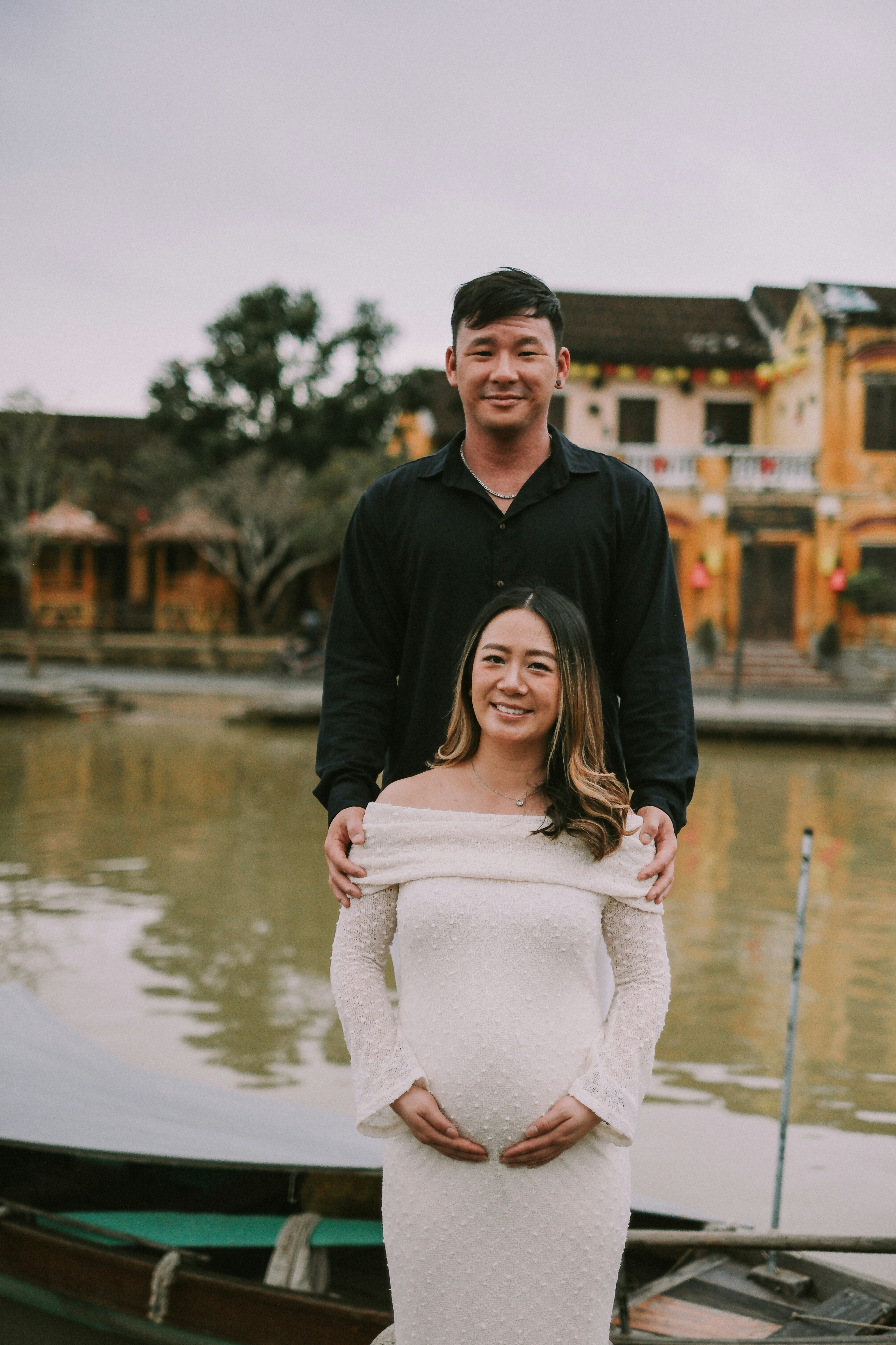 Pregnant woman and man by river with buildings
