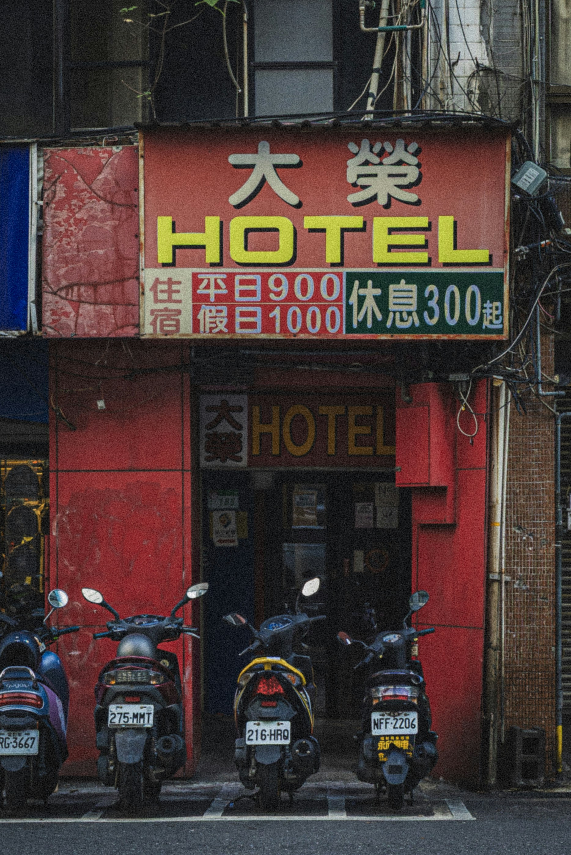 Motorcycles parked outside a red hotel entrance.