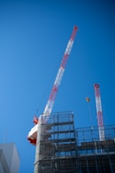 Two construction cranes against a clear blue sky.