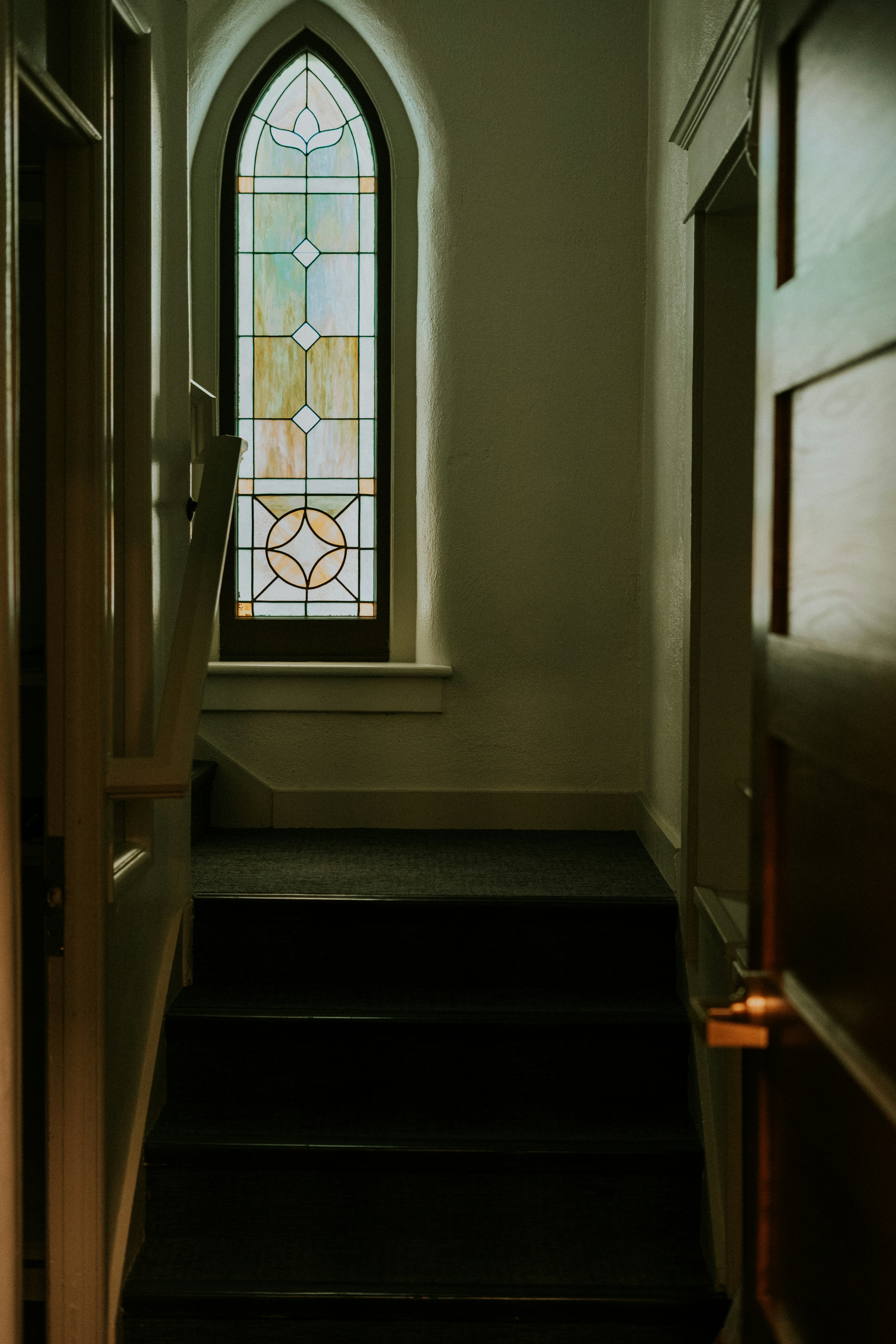 Staircase leading to a arched stained glass window