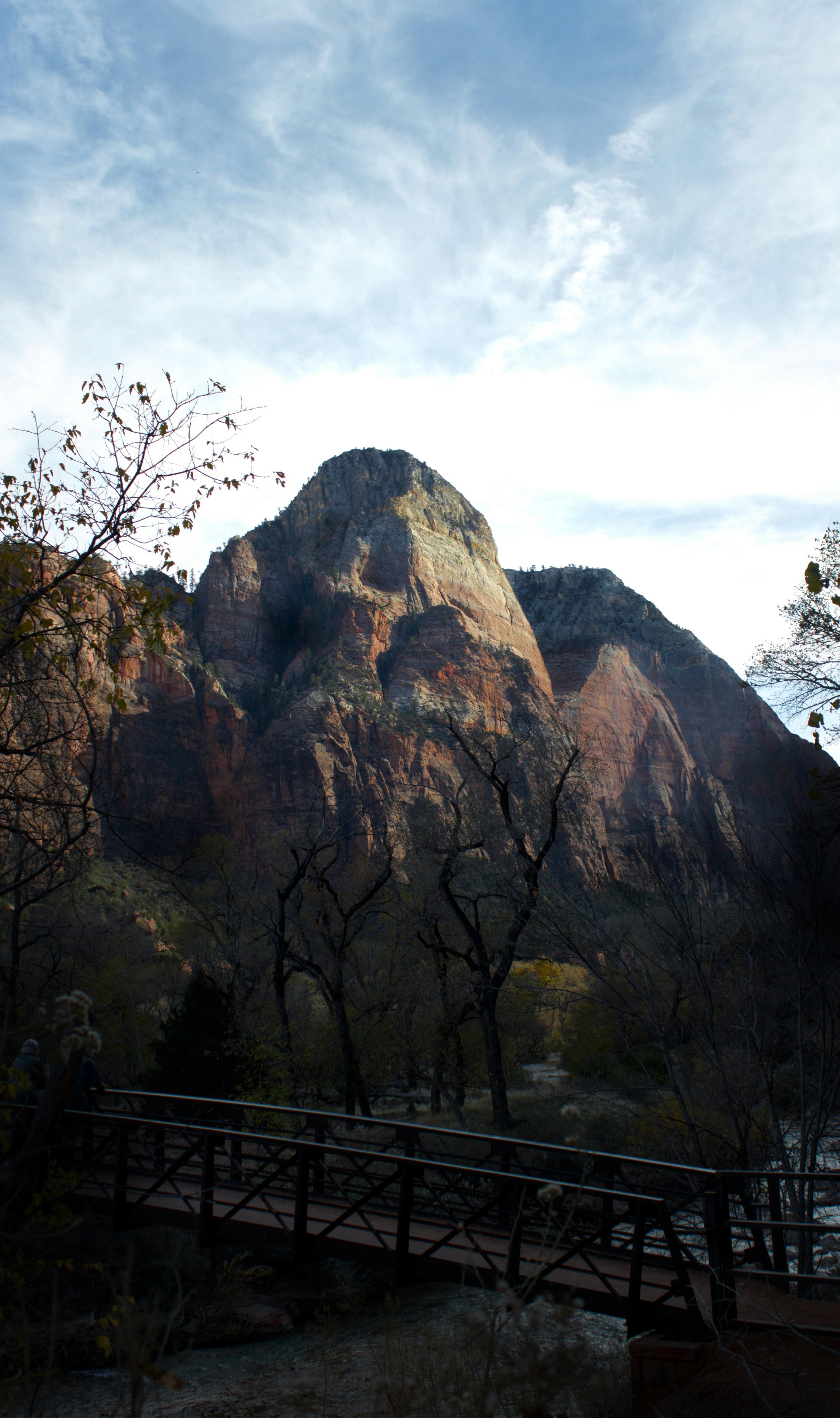 A bridge crosses a river below a large mountain.