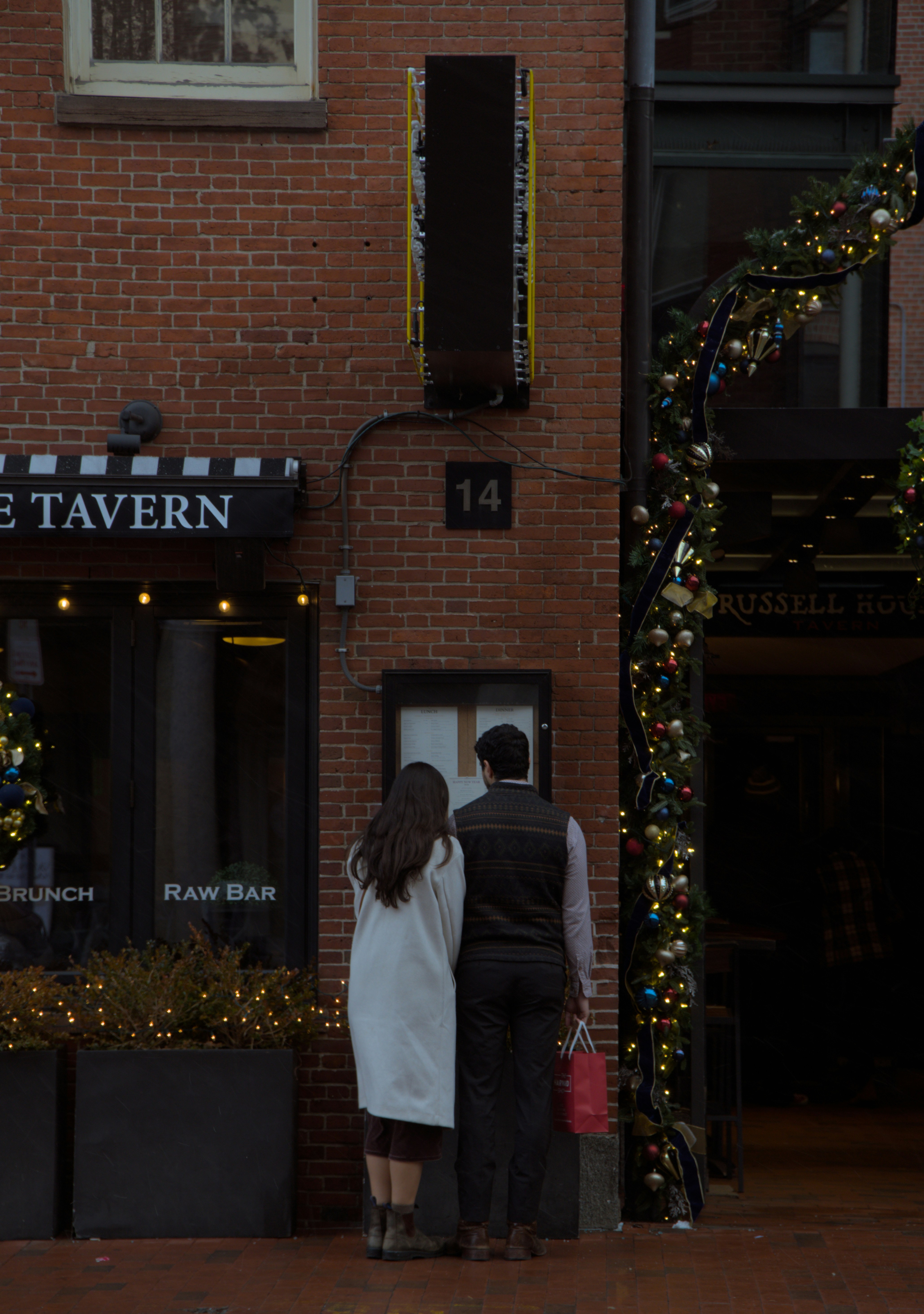 Couple looking at menu outside brick building