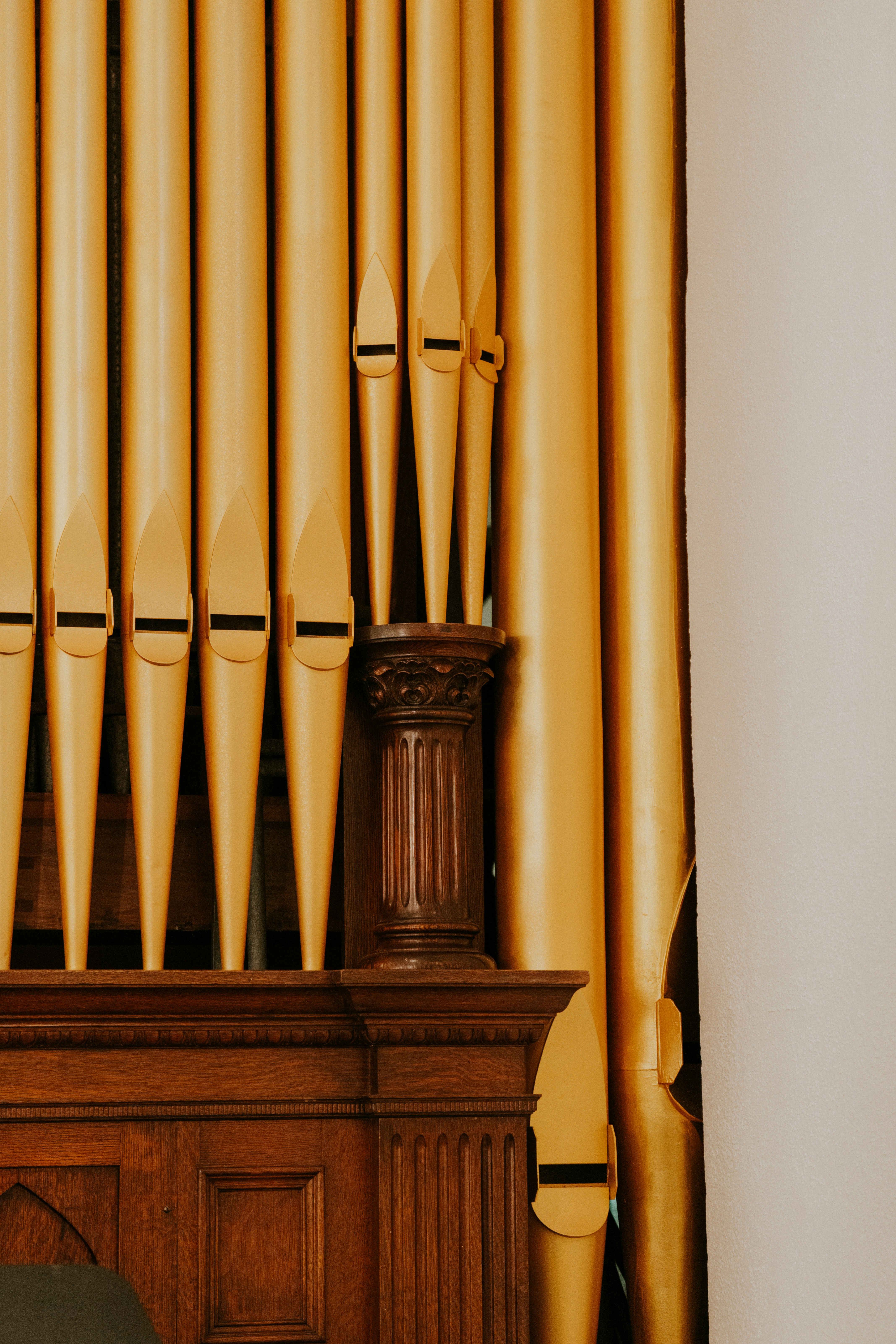 Close-up of golden organ pipes on wooden structure.