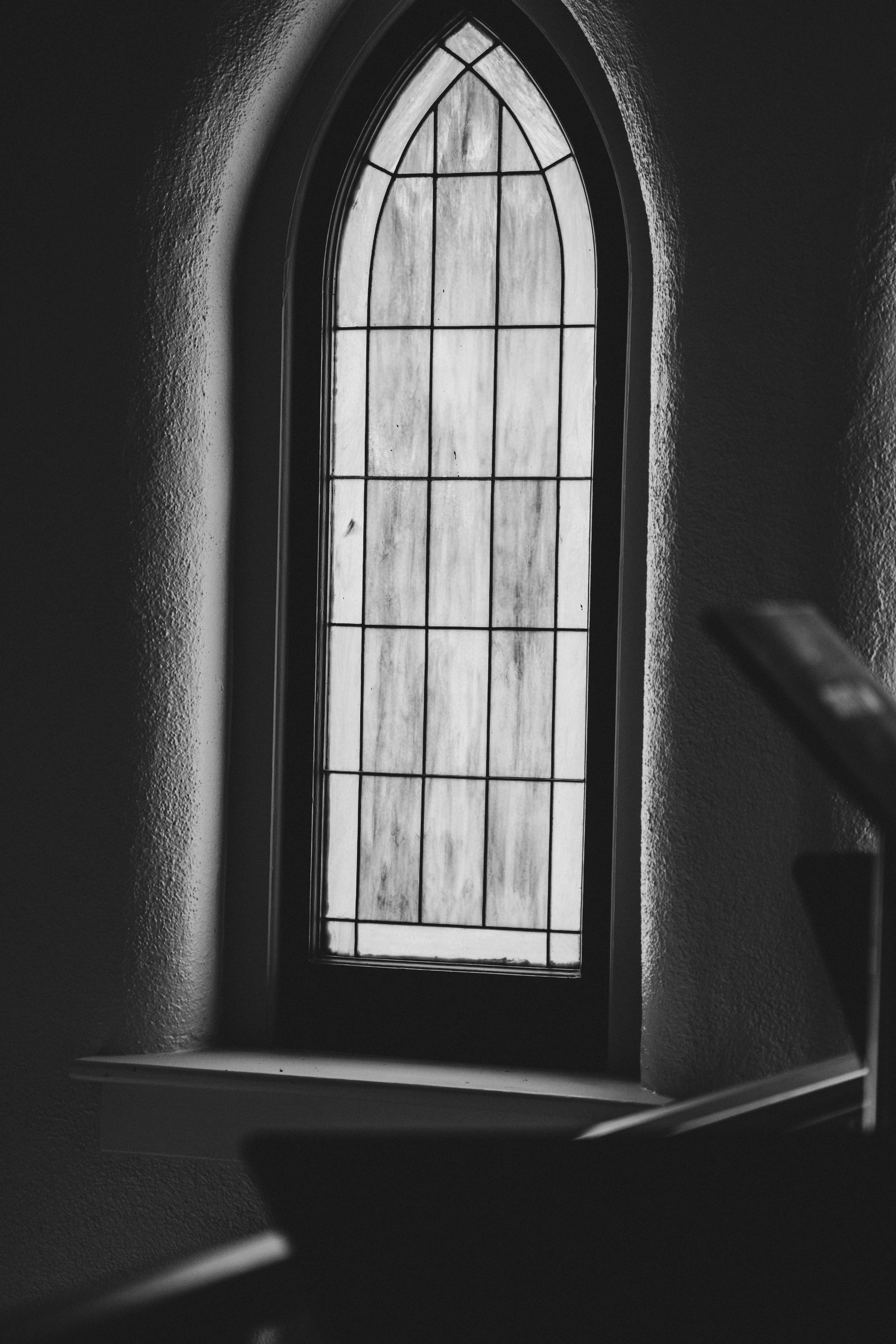 Arched stained glass window in a dimly lit room