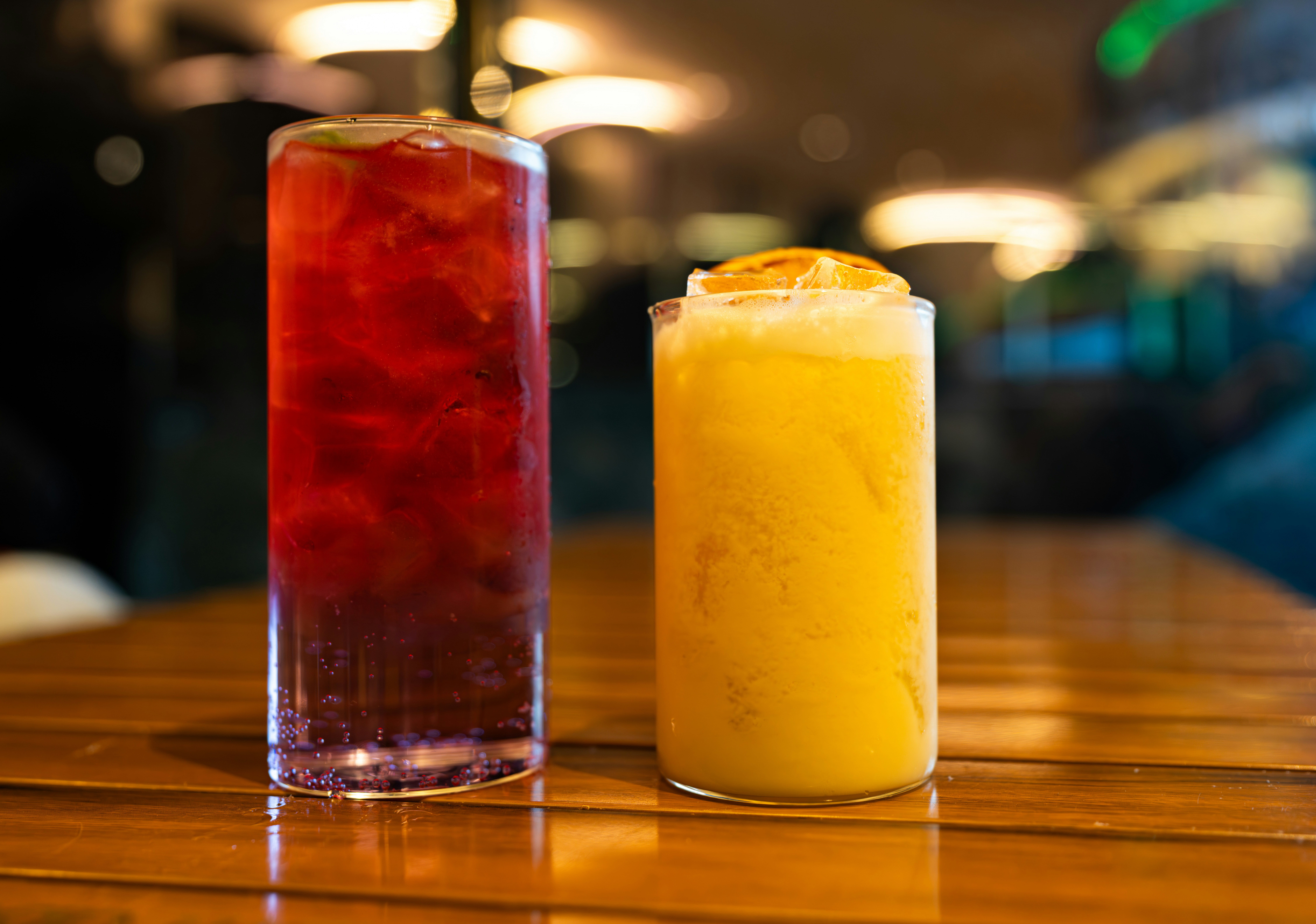 Dua minuman berwarna-warni di atas meja kayu