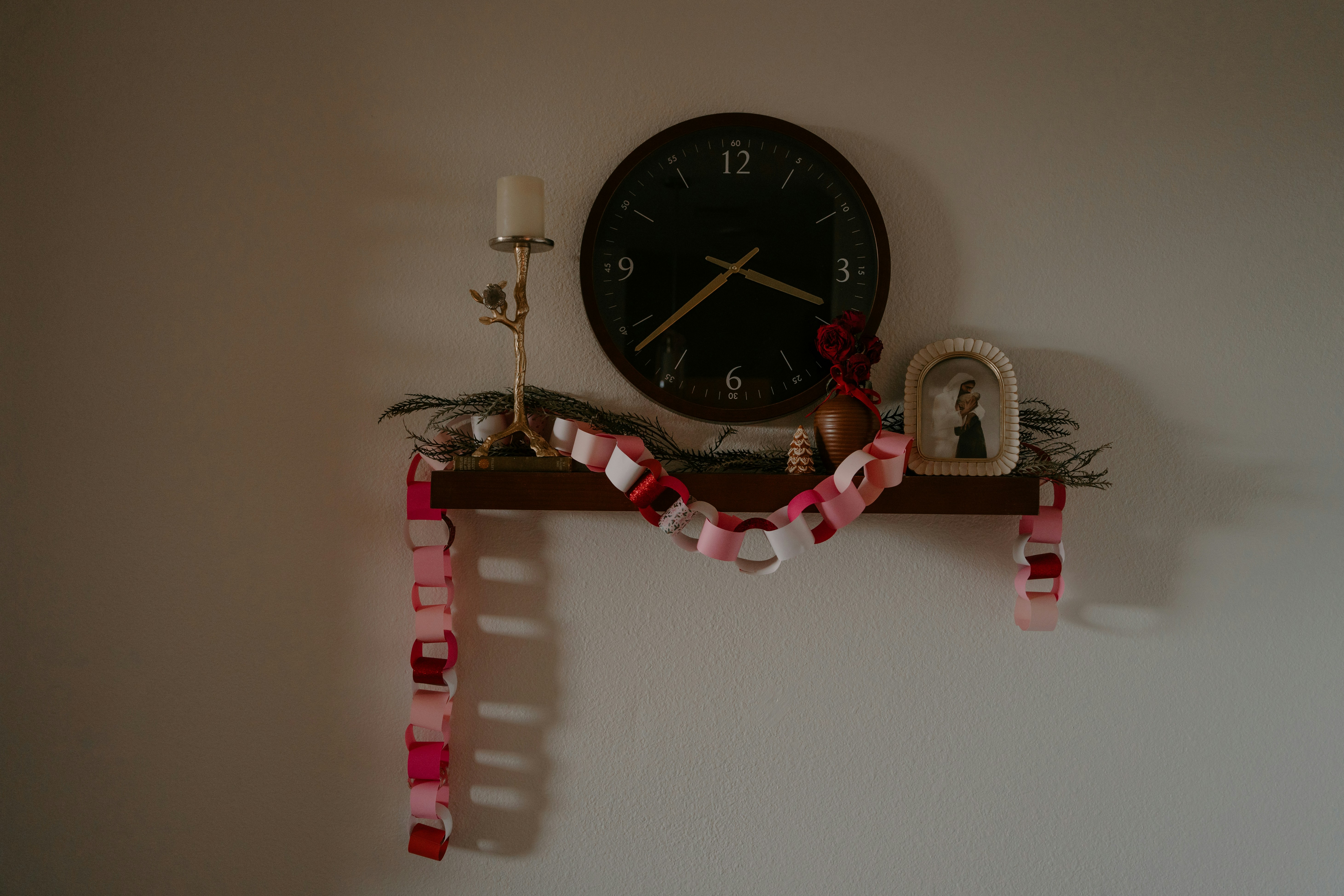 時計、キャンドル、紙のチェーンの飾りが置かれた棚。