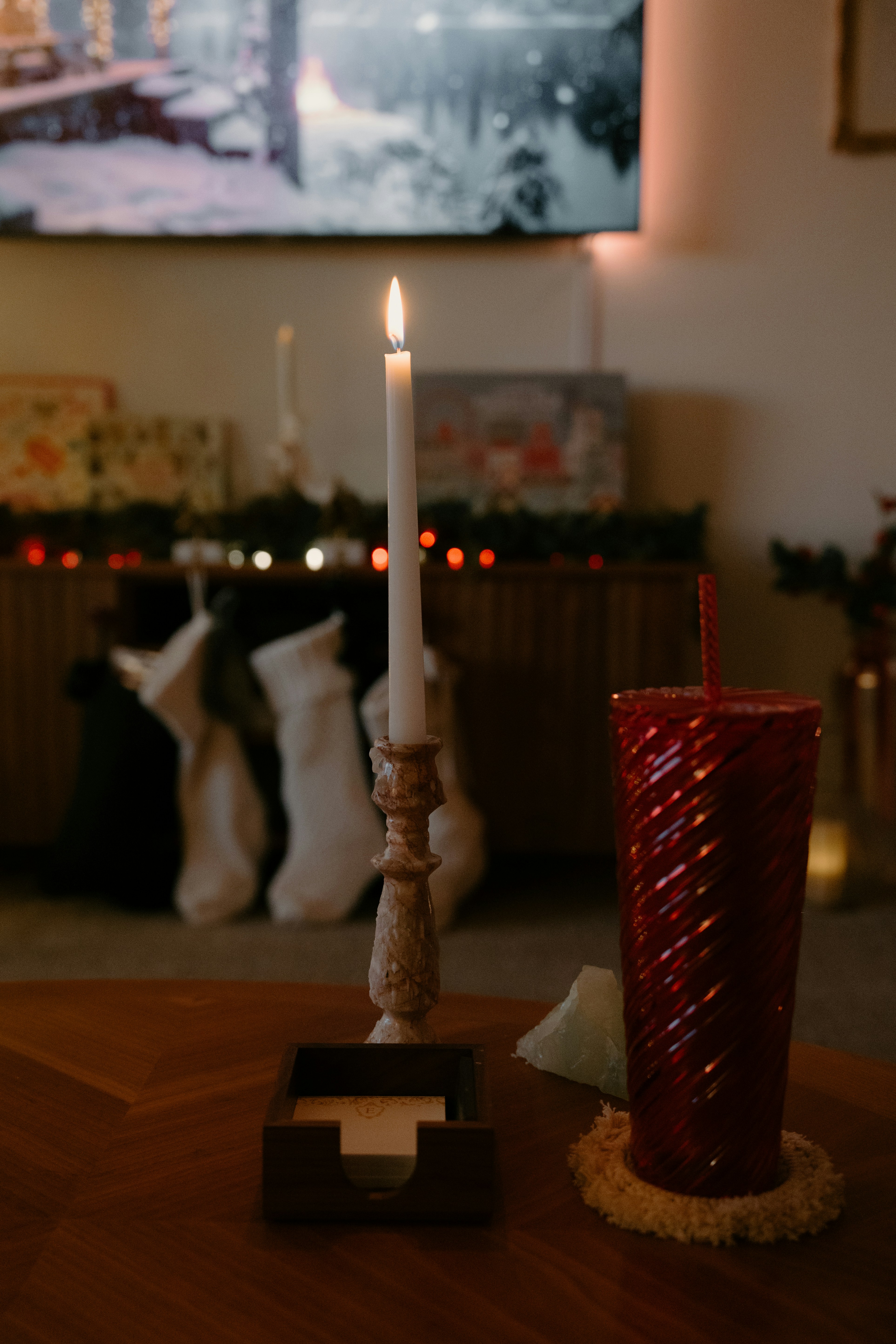 Candle lit with a red cup on a table.