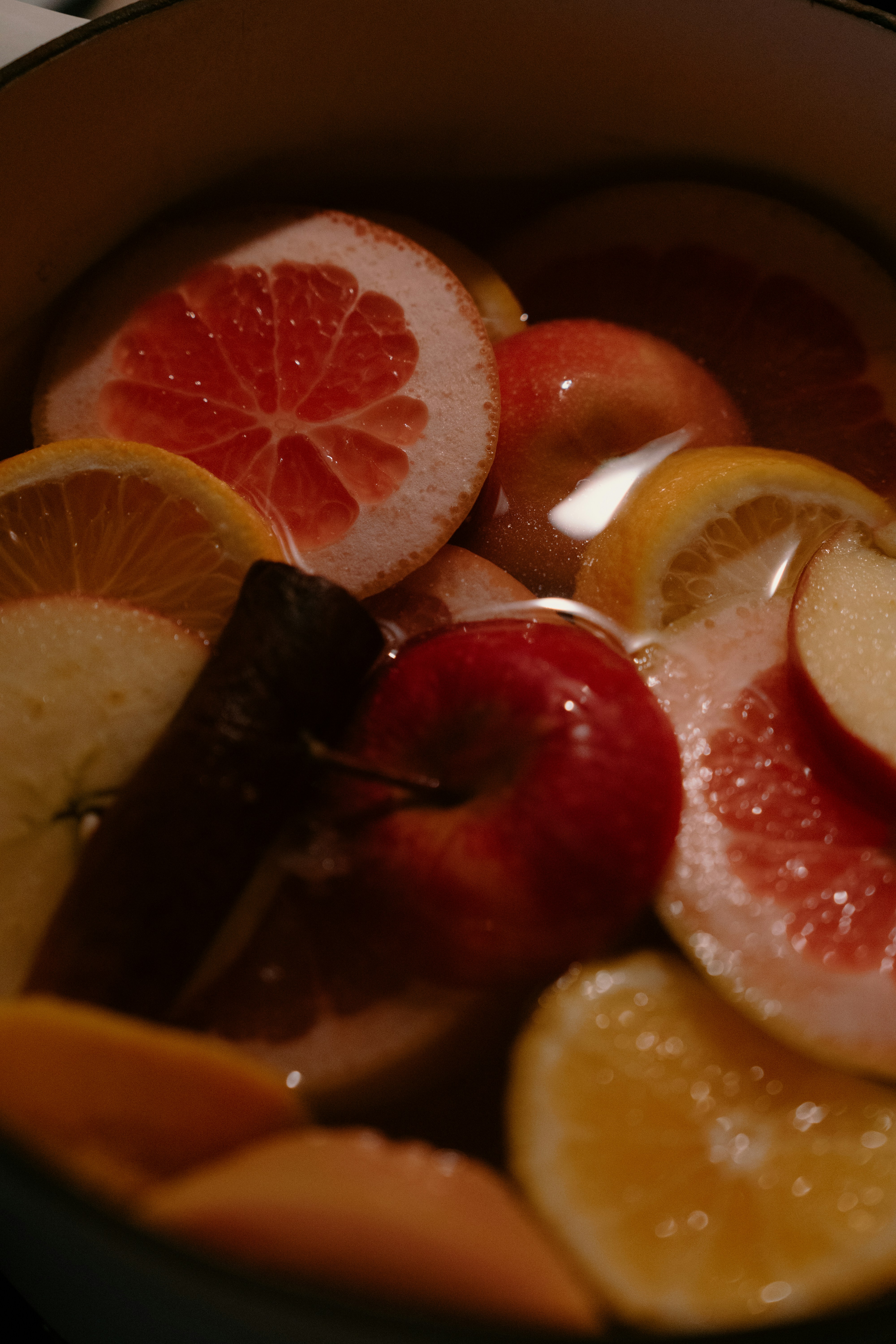 Sliced oranges, apples, and grapefruit with cinnamon sticks.