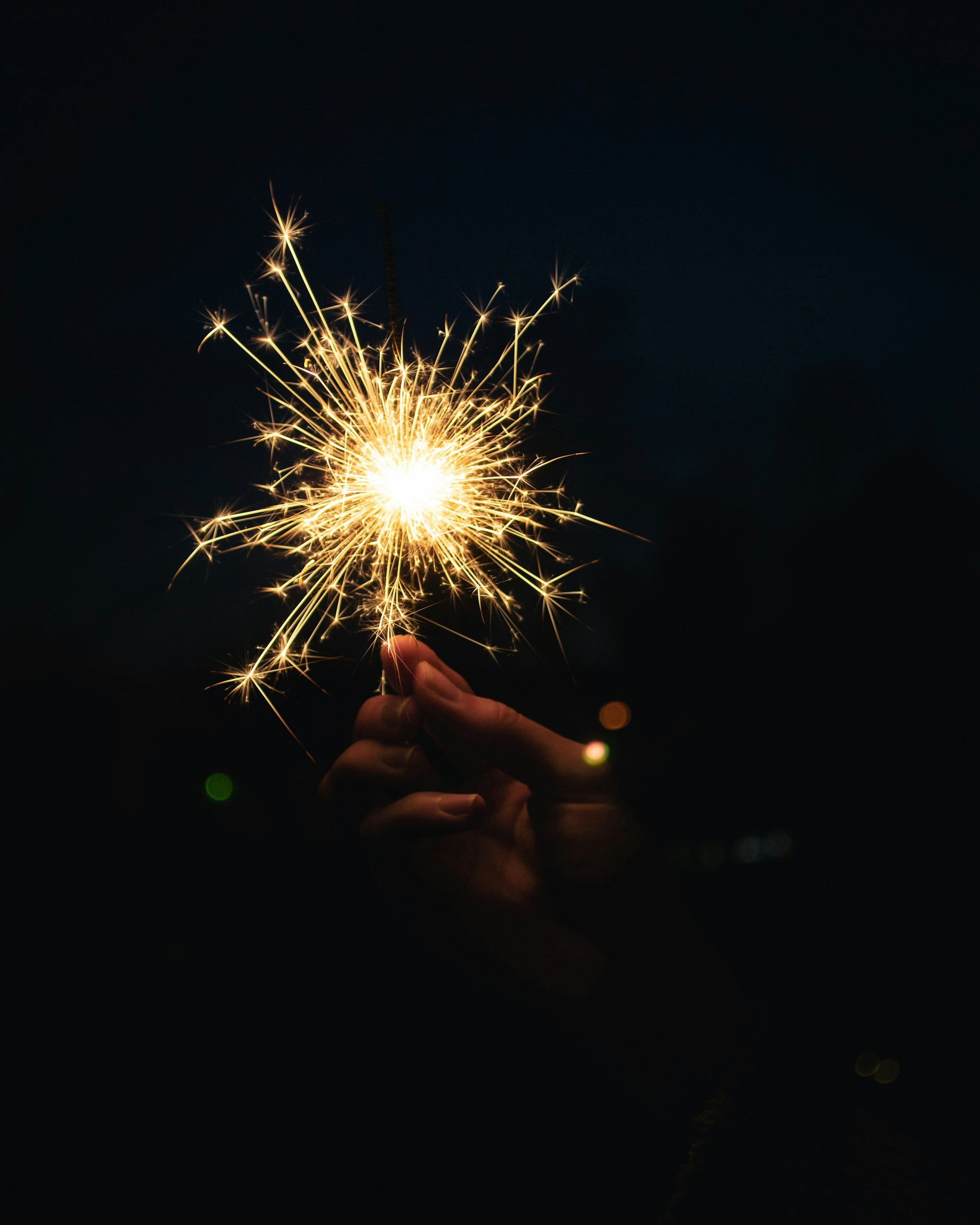 Hand holding a sparkling sparkler at night