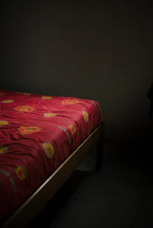 A bed with a red patterned comforter