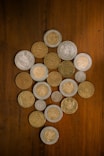 Collection of various coins arranged on a wooden surface