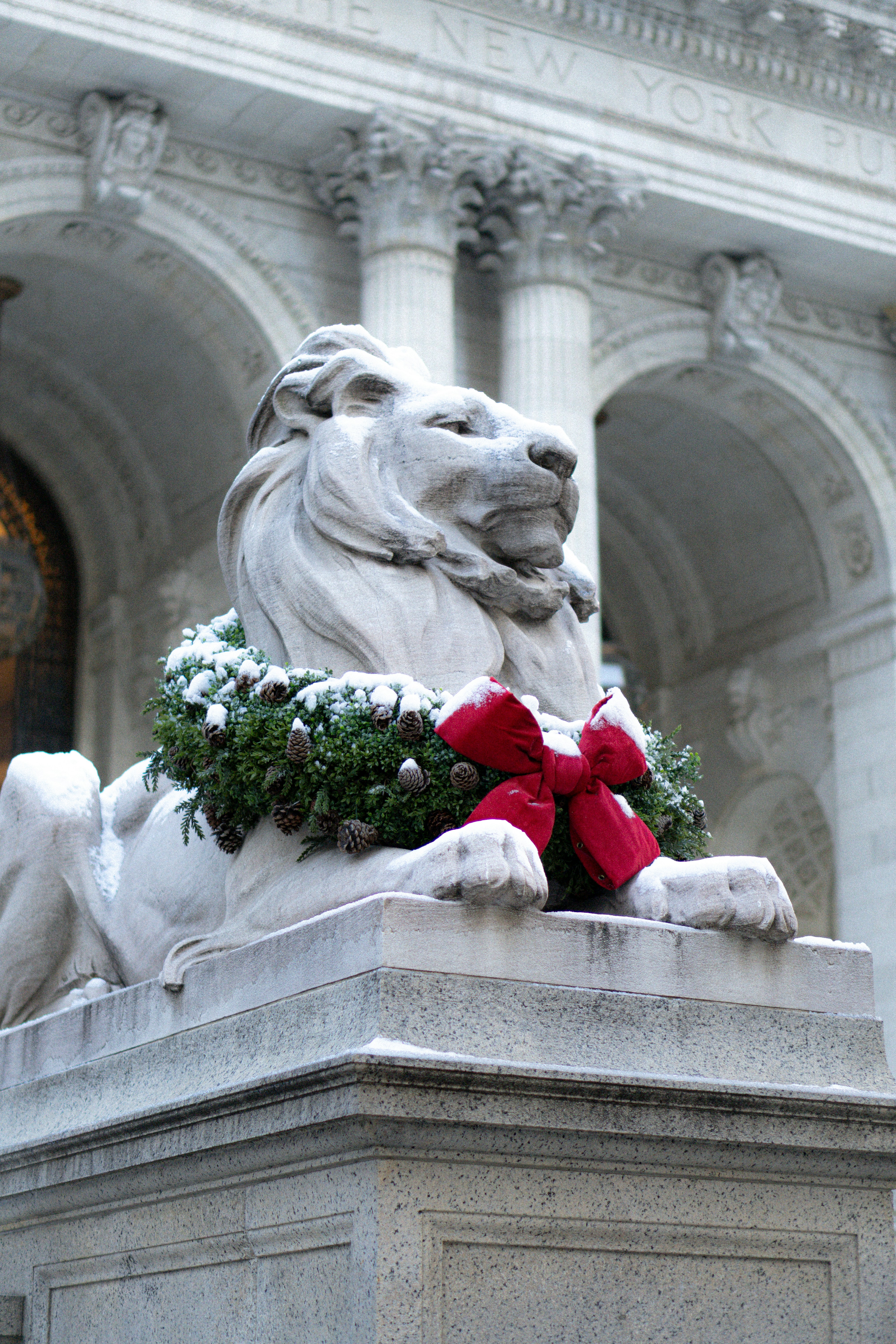 Stone lion statue decorated with christmas wreath and bow.