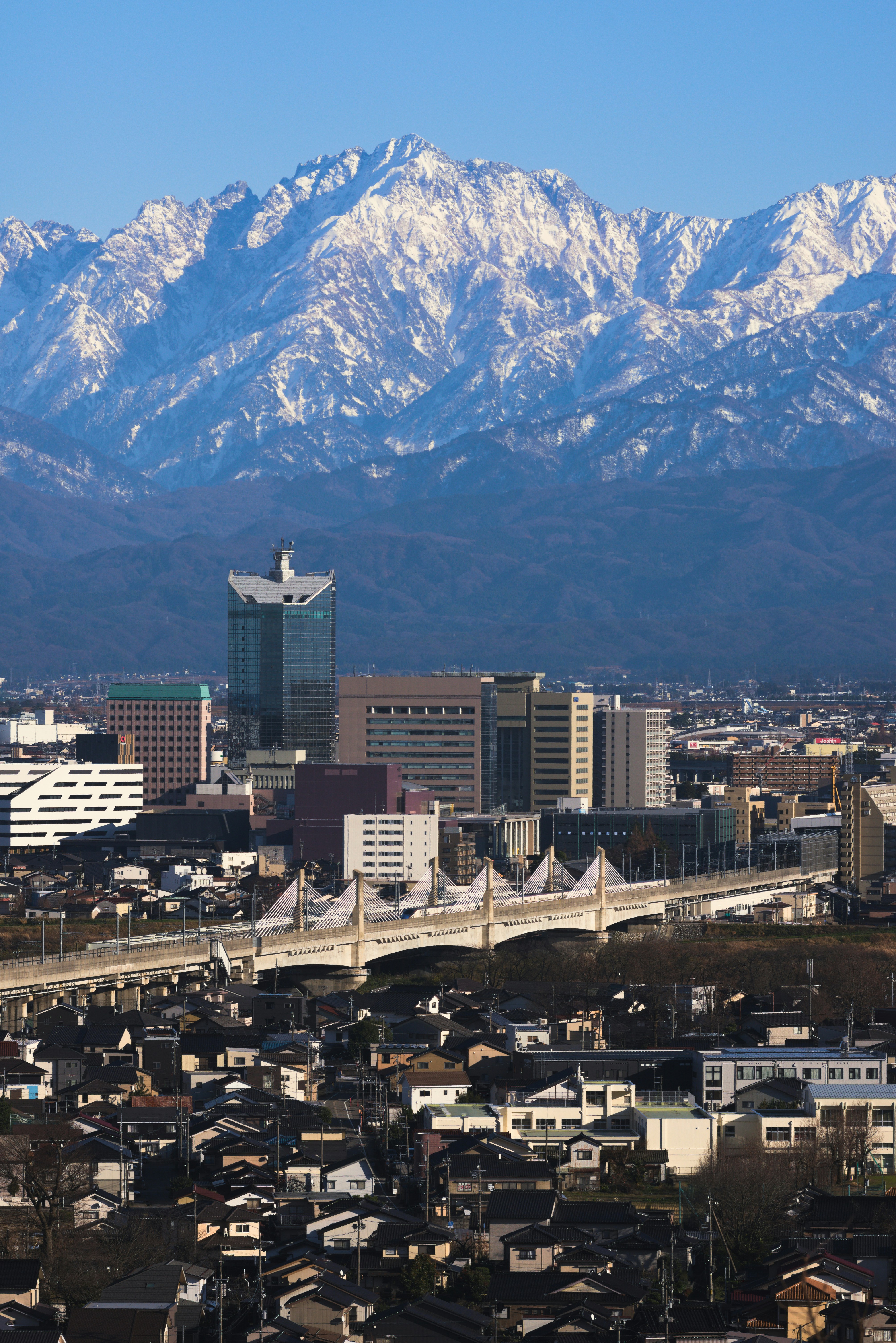 City skyline with snow-capped mountains in the background.