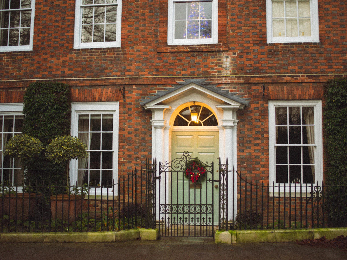 Red brick house with a green front door and a Christmas wreath