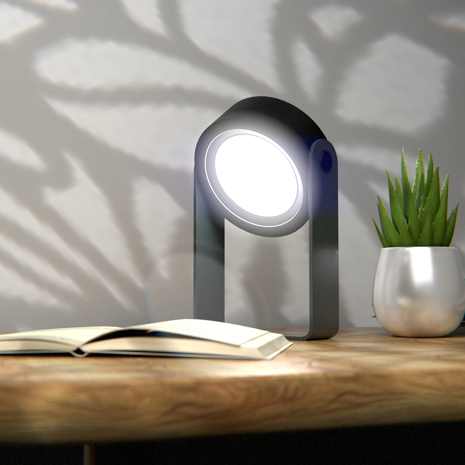 Round desk grow lamp shining beside a small succulent and an open book