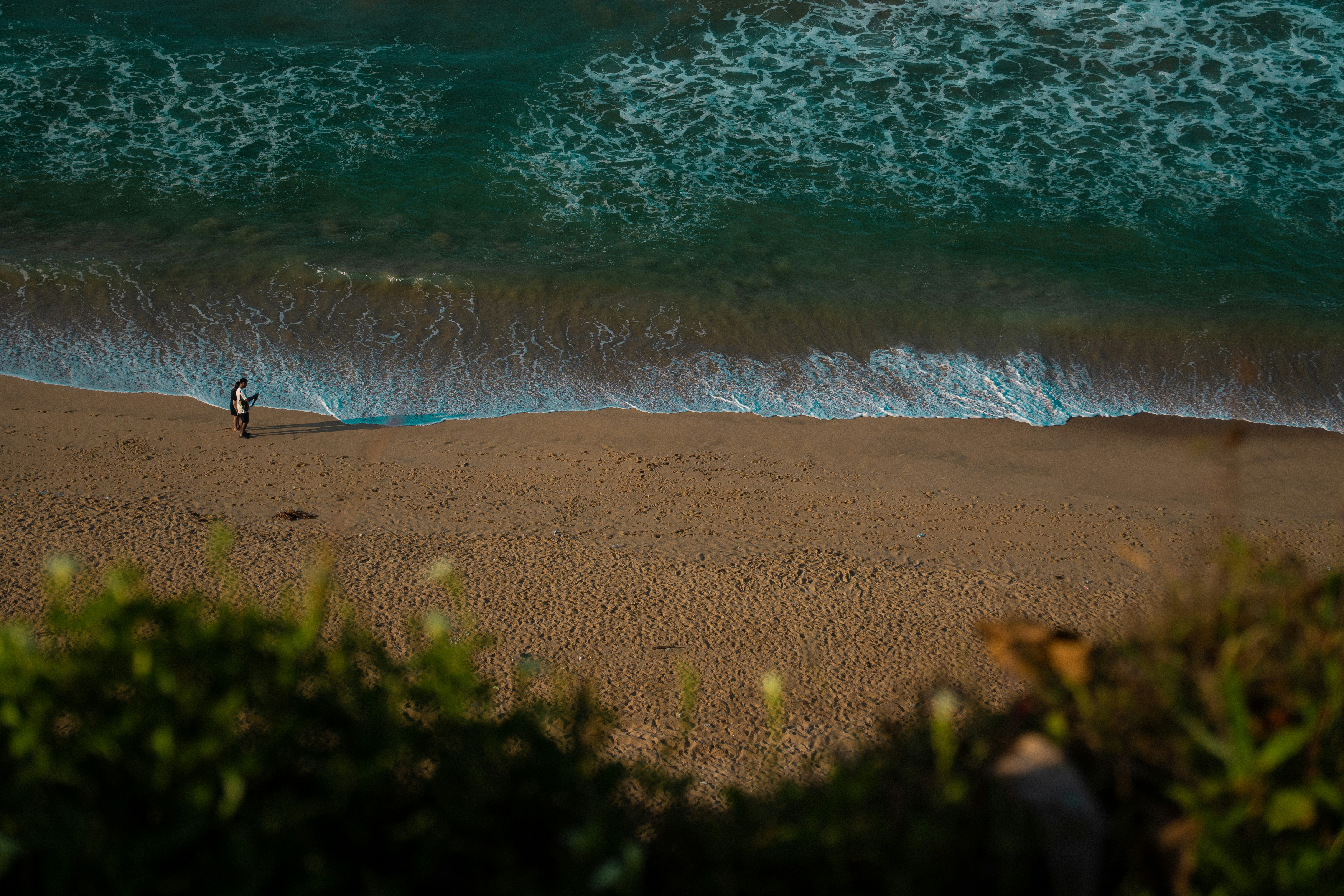 Une personne marche le long d’une plage de sable où les vagues s’écrasent.