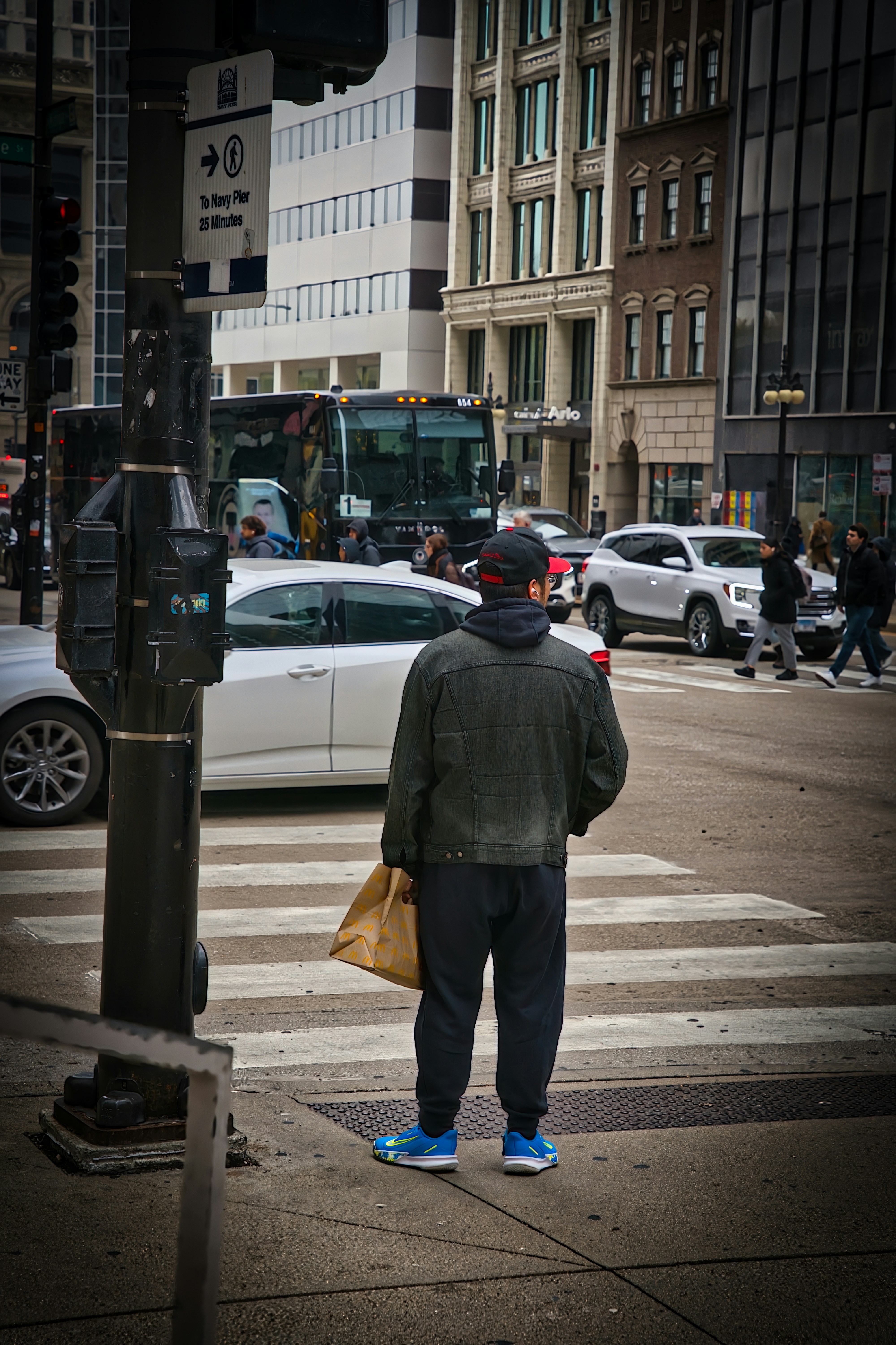 Man holding bag waits at city crosswalk