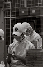 Chefs in uniform preparing food in a kitchen.