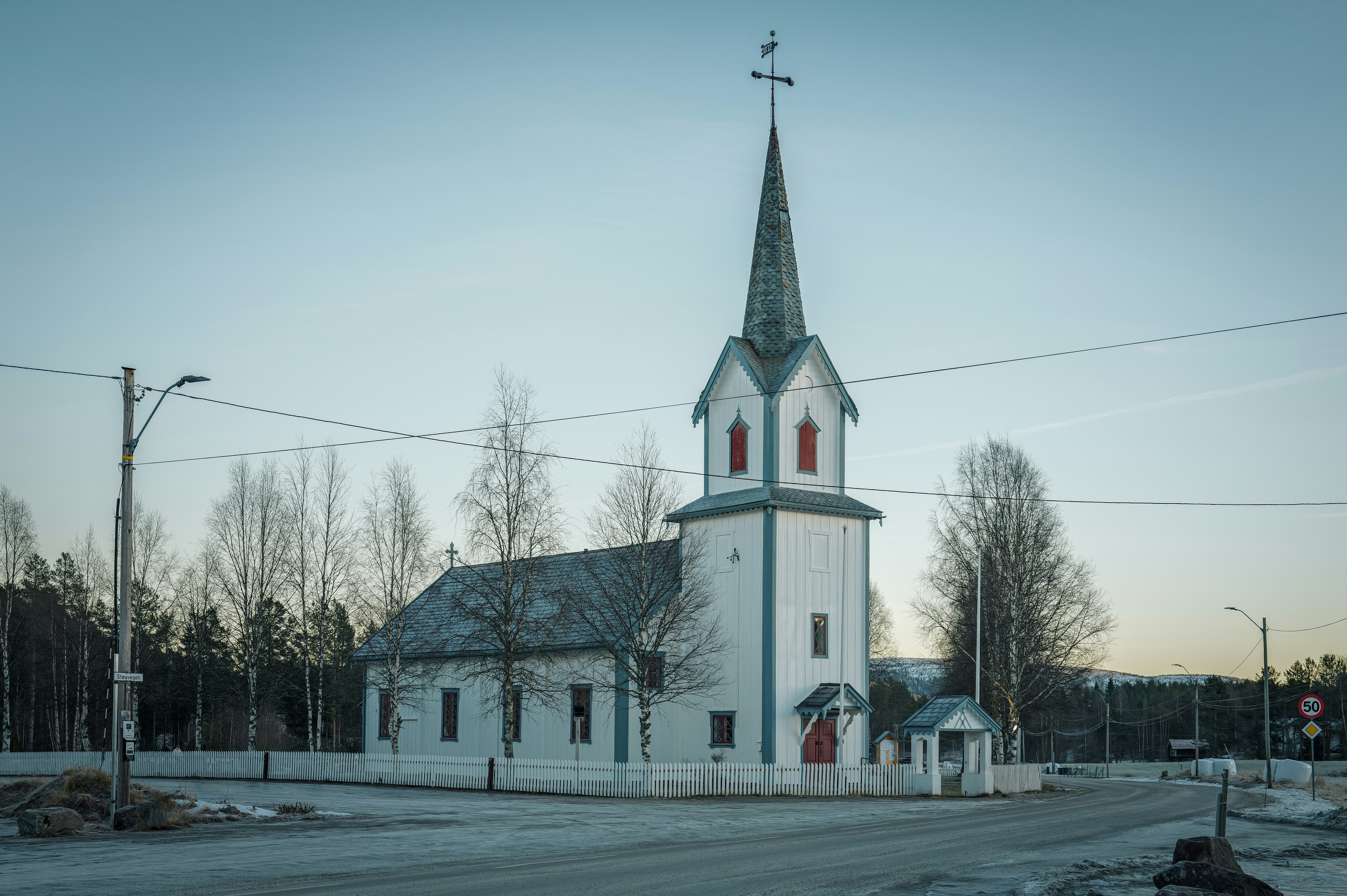 White wooden church with a tall steeple.