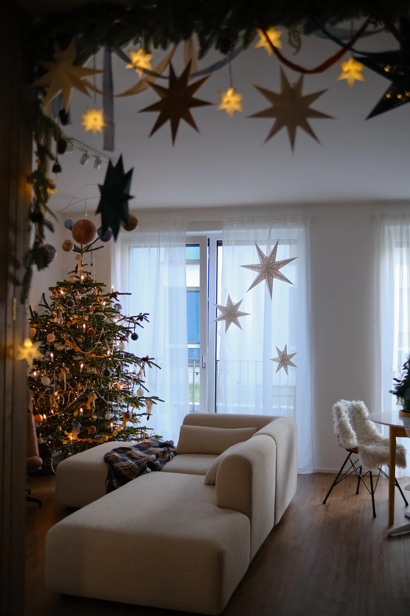A cozy living room decorated for the holidays with a lit Christmas tree and soft string lights