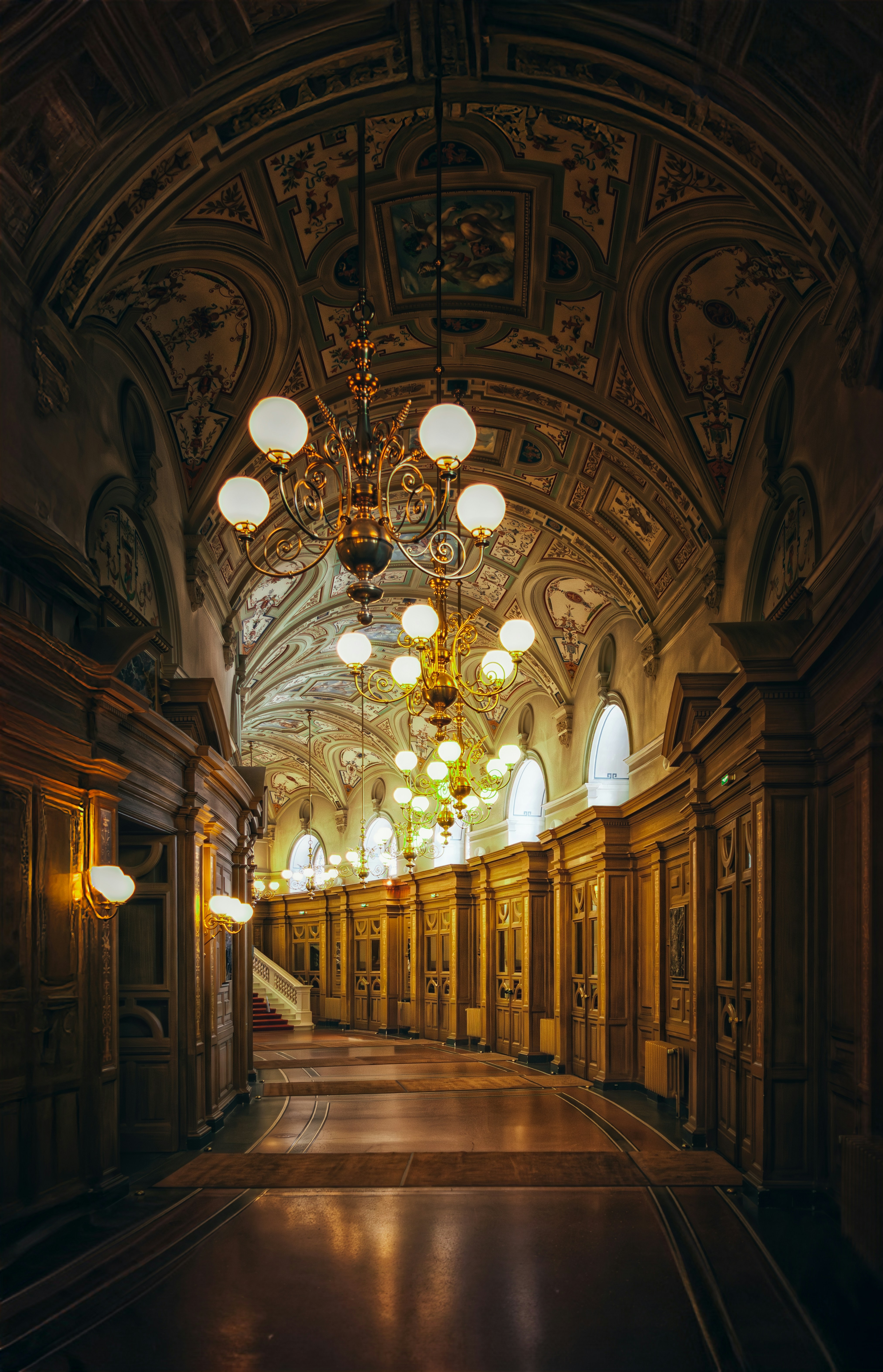 Corridoio ornato con lampadari e soffitto dettagliato.