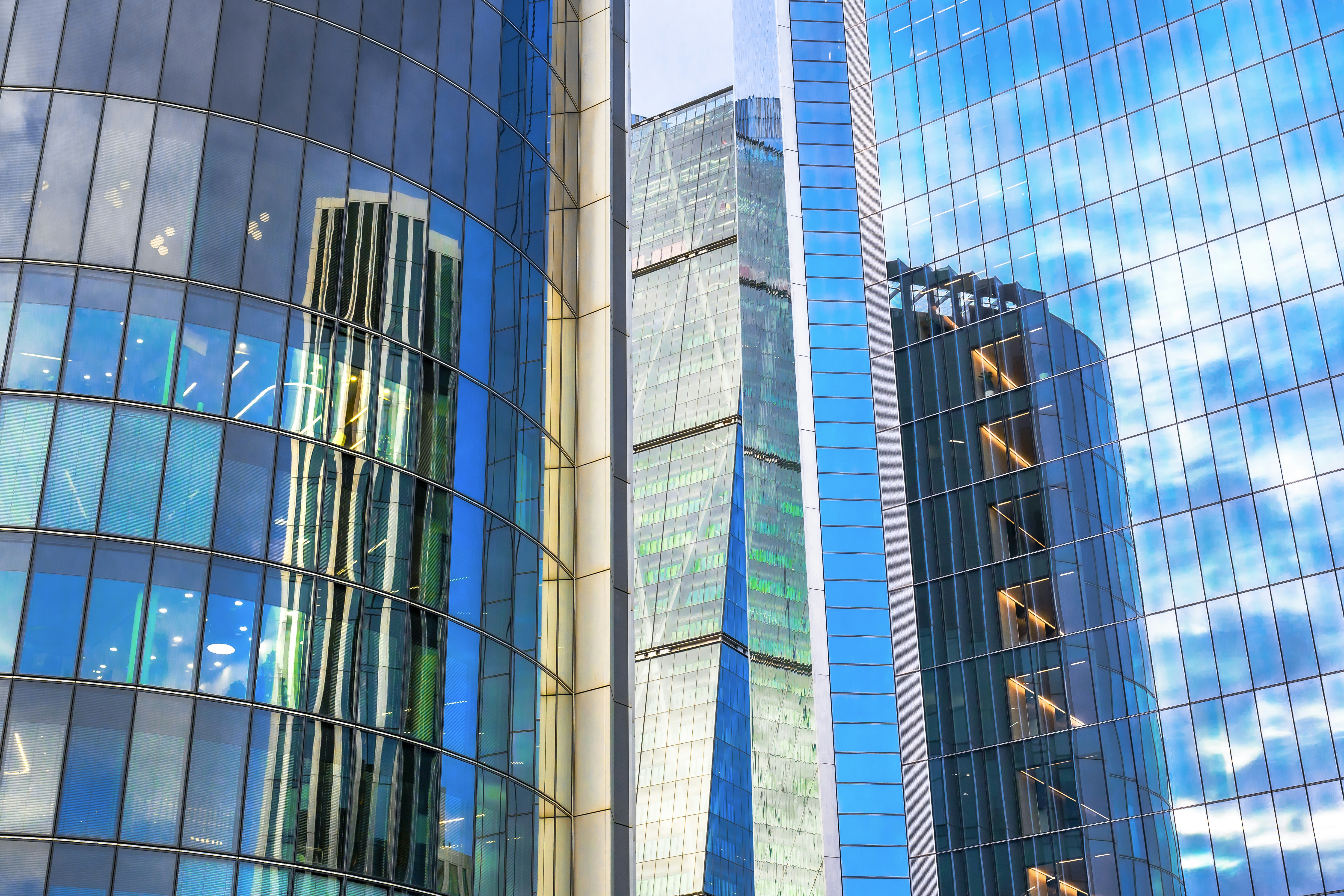 Modern glass skyscrapers reflecting blue sky and clouds