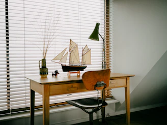 Desk with model sailboat and lamp