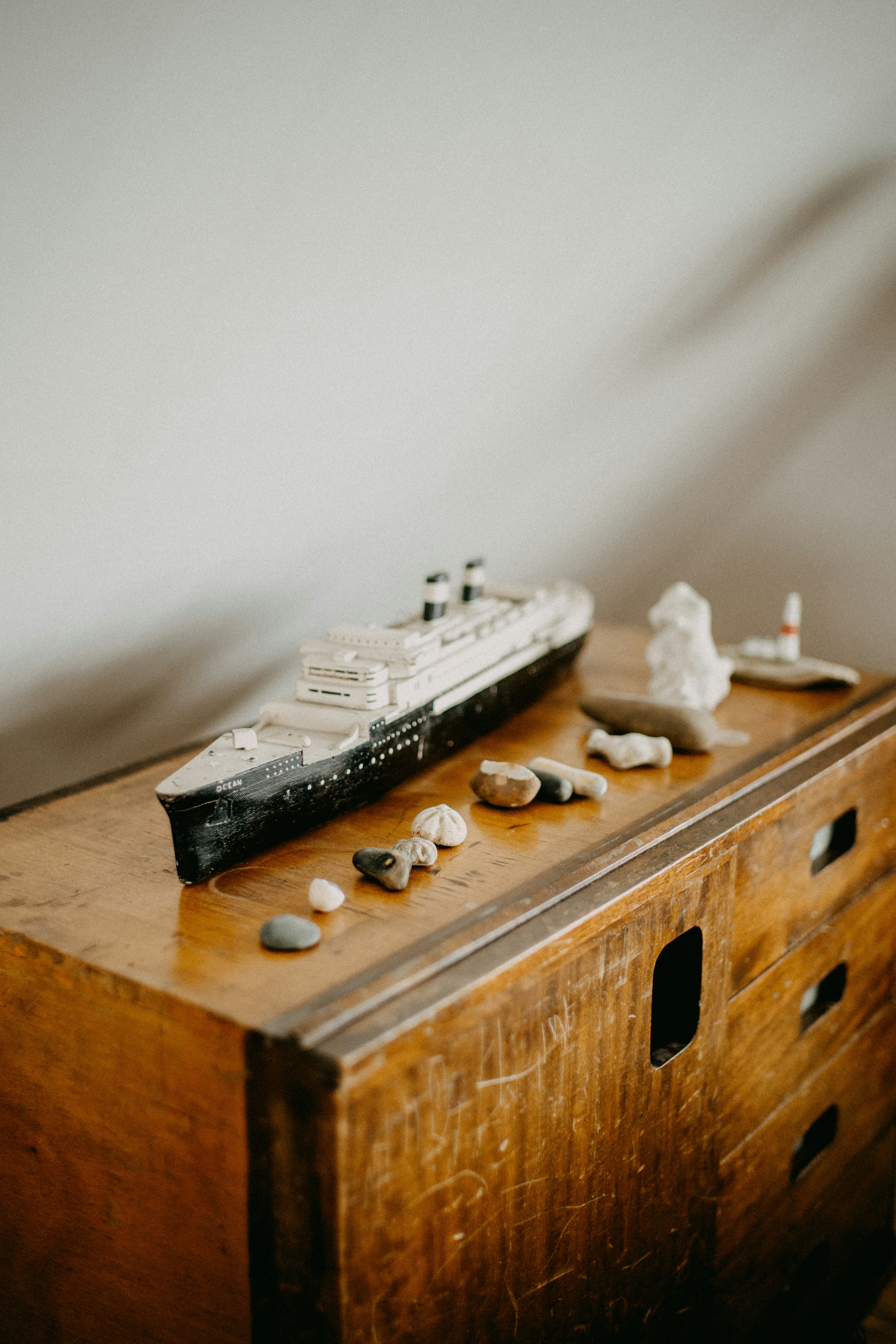 Model ship and stones on wooden dresser