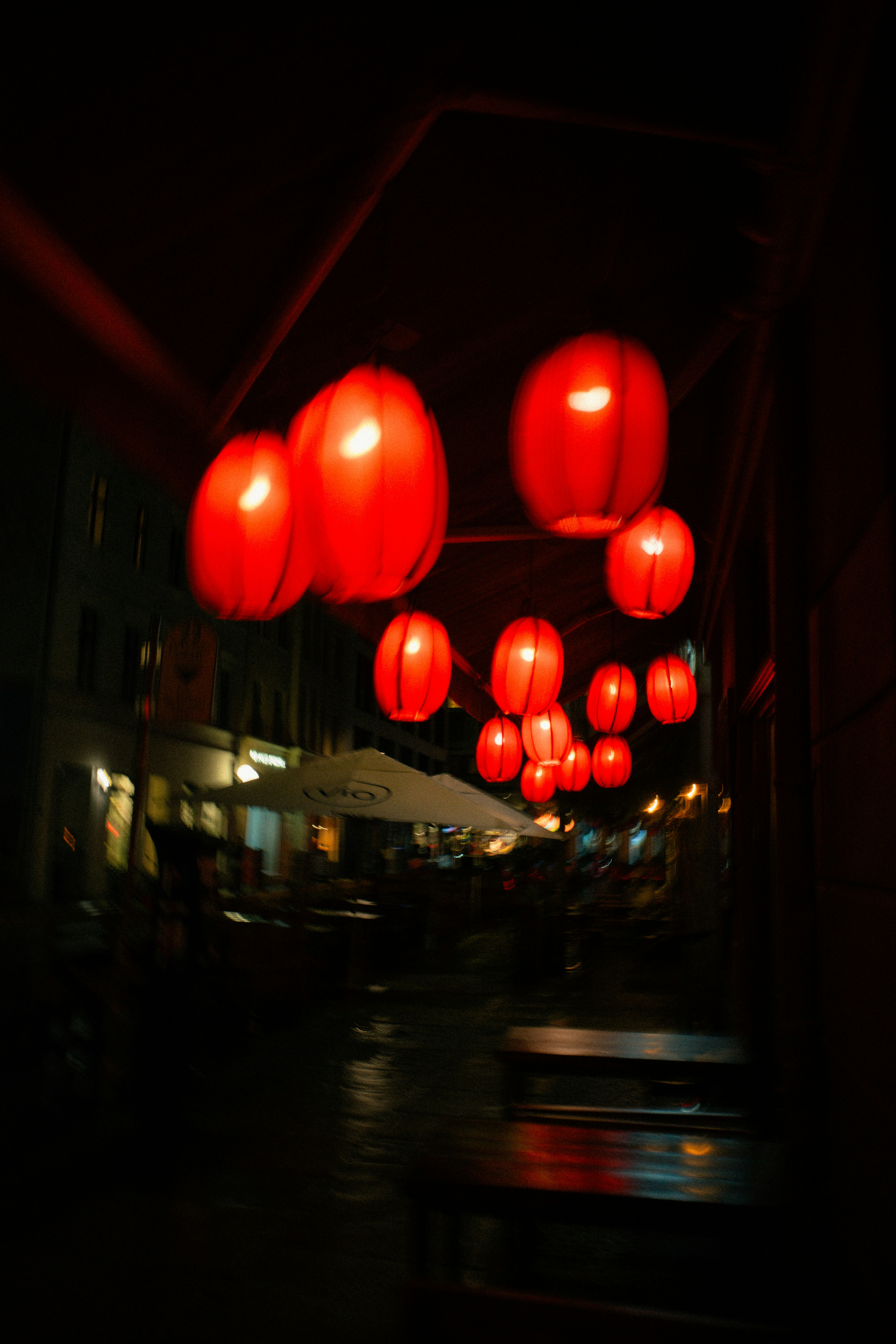 Red lanterns illuminate a dark street at night.