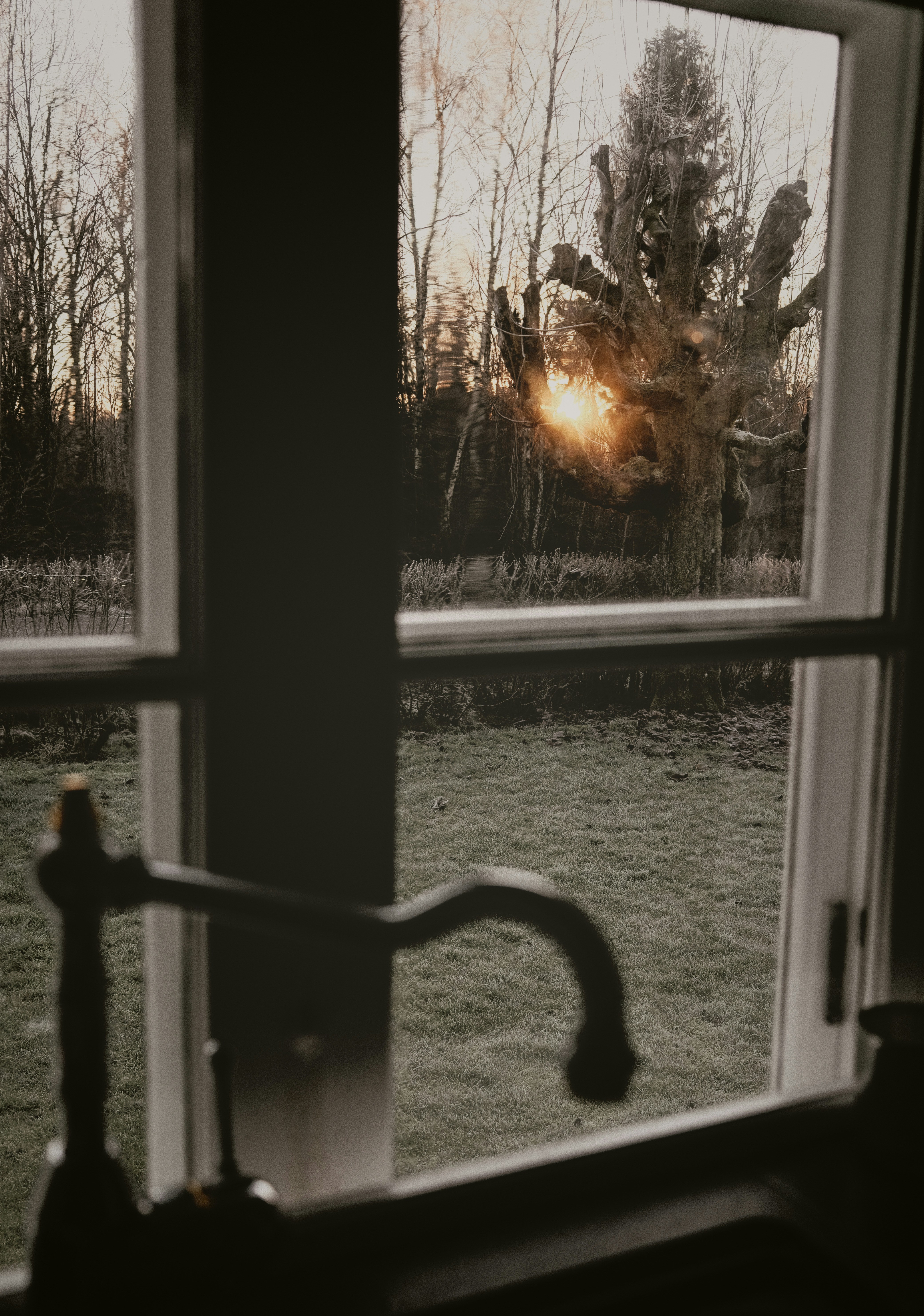 Sunset viewed through a window with a faucet.