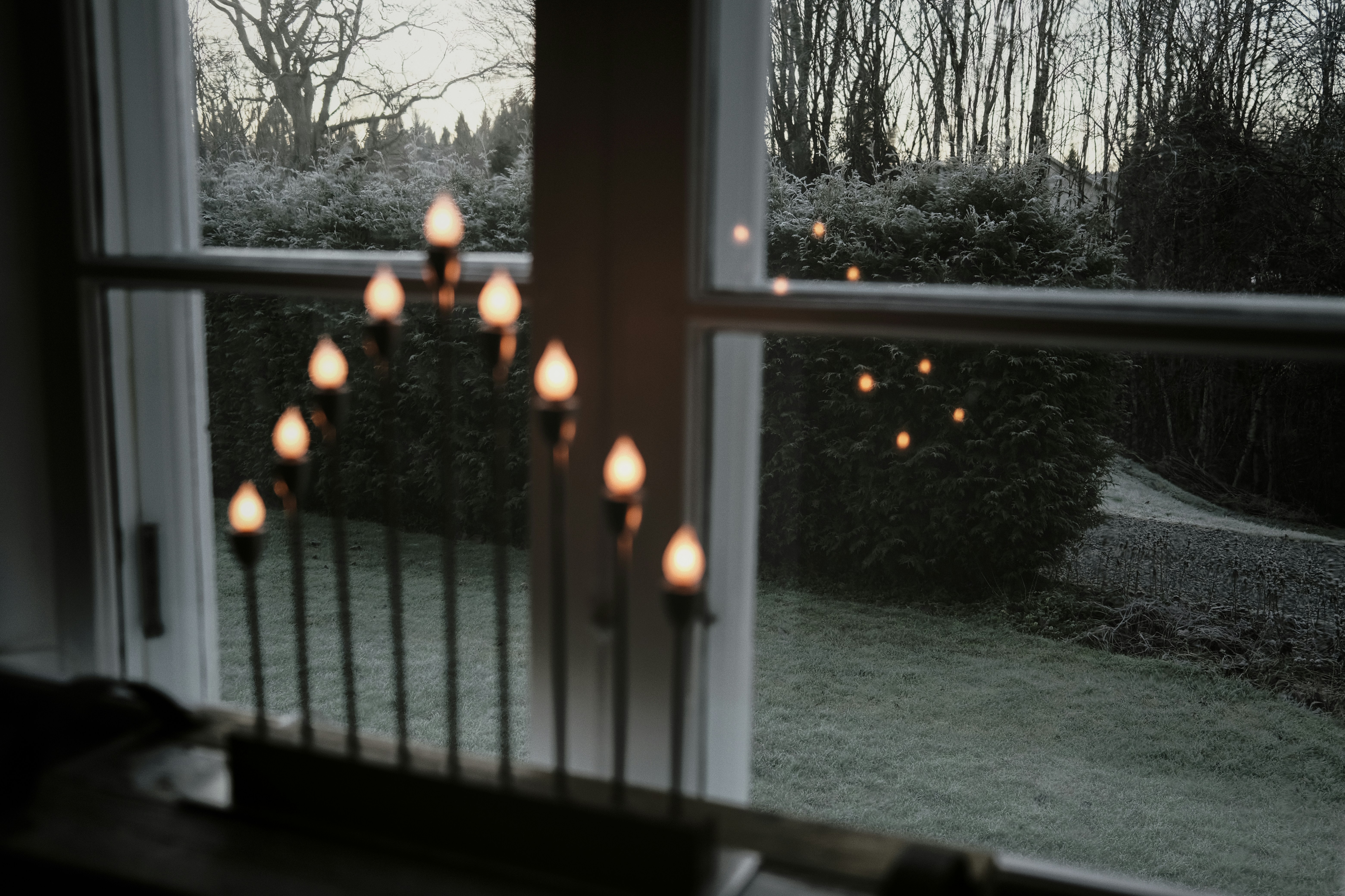 Candles in a window overlooking a garden