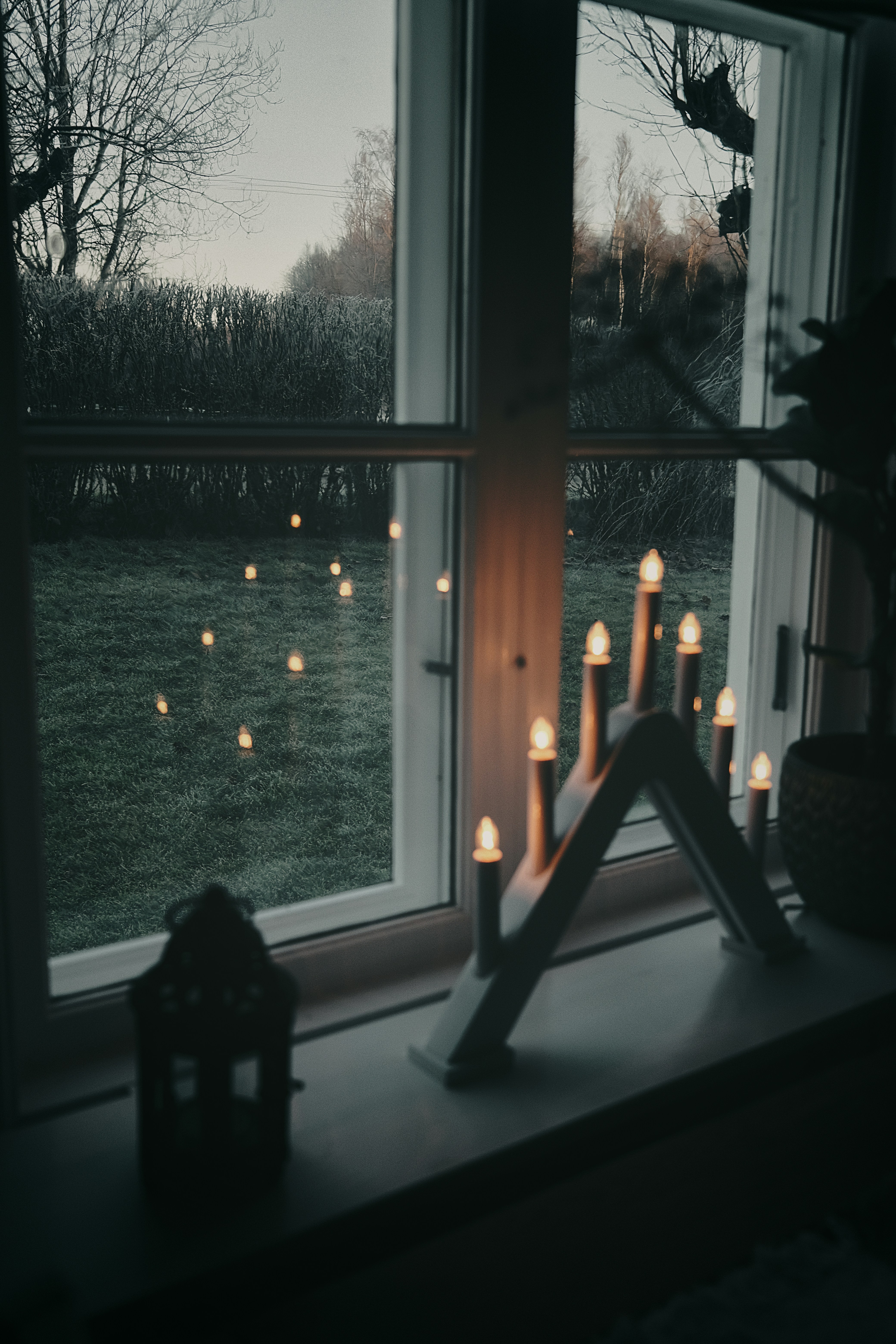 Candle arch and lantern on windowsill overlooking garden
