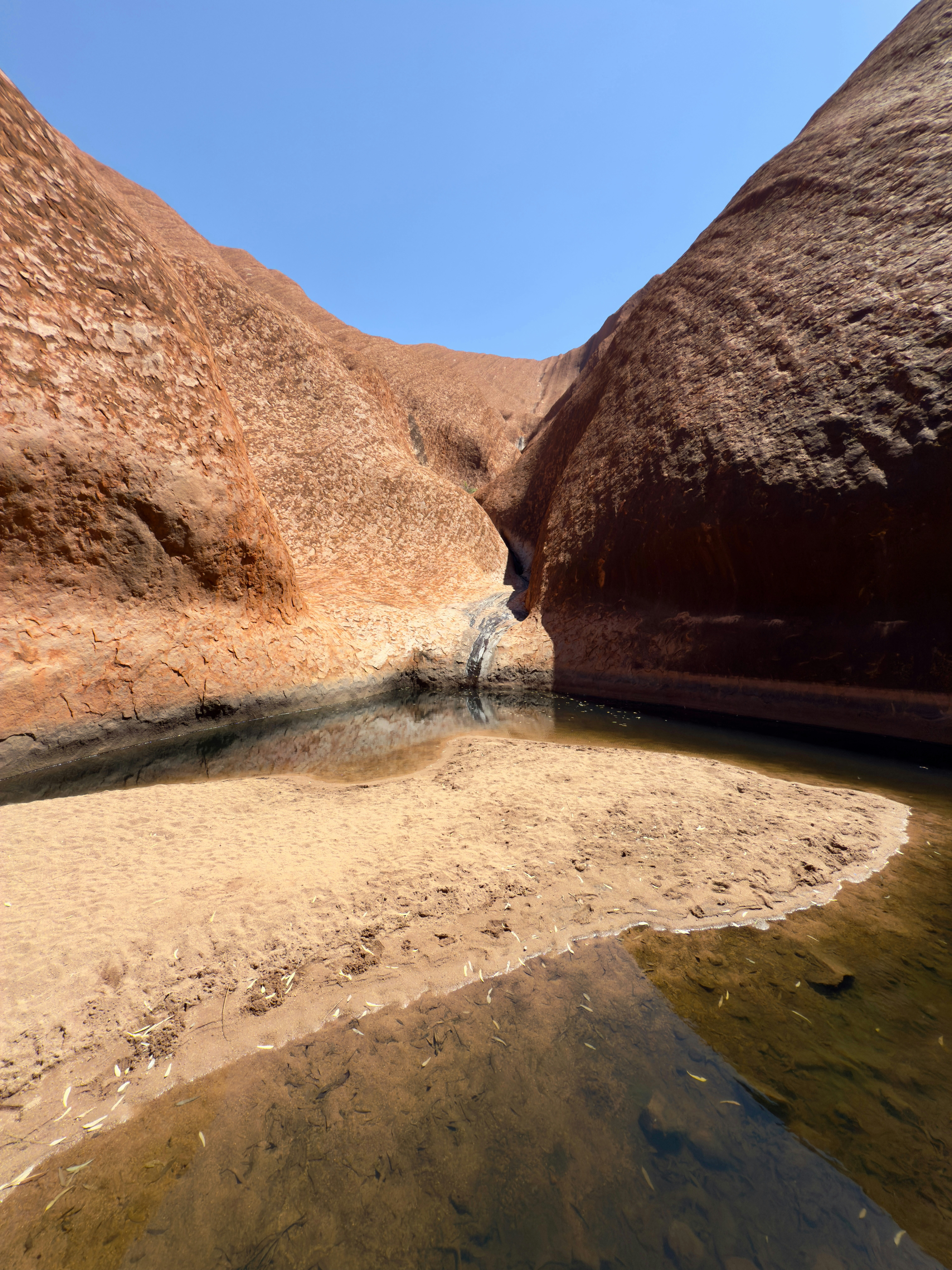 Red rock formations with a small stream and reflection