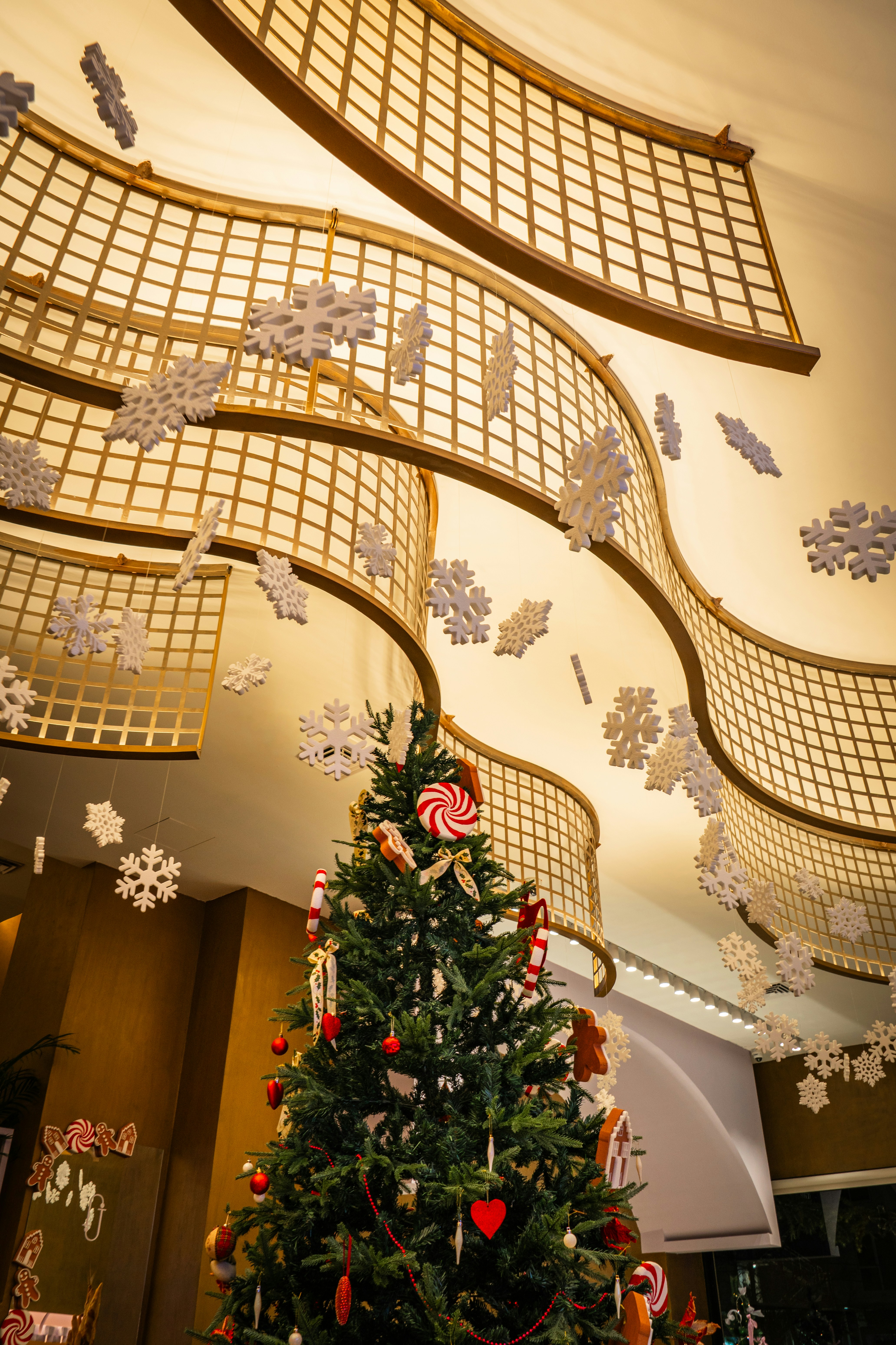 Decorated christmas tree with snowflakes hanging from ceiling.