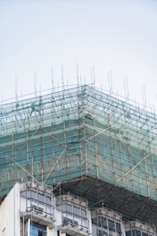 Building under construction with scaffolding and green netting.