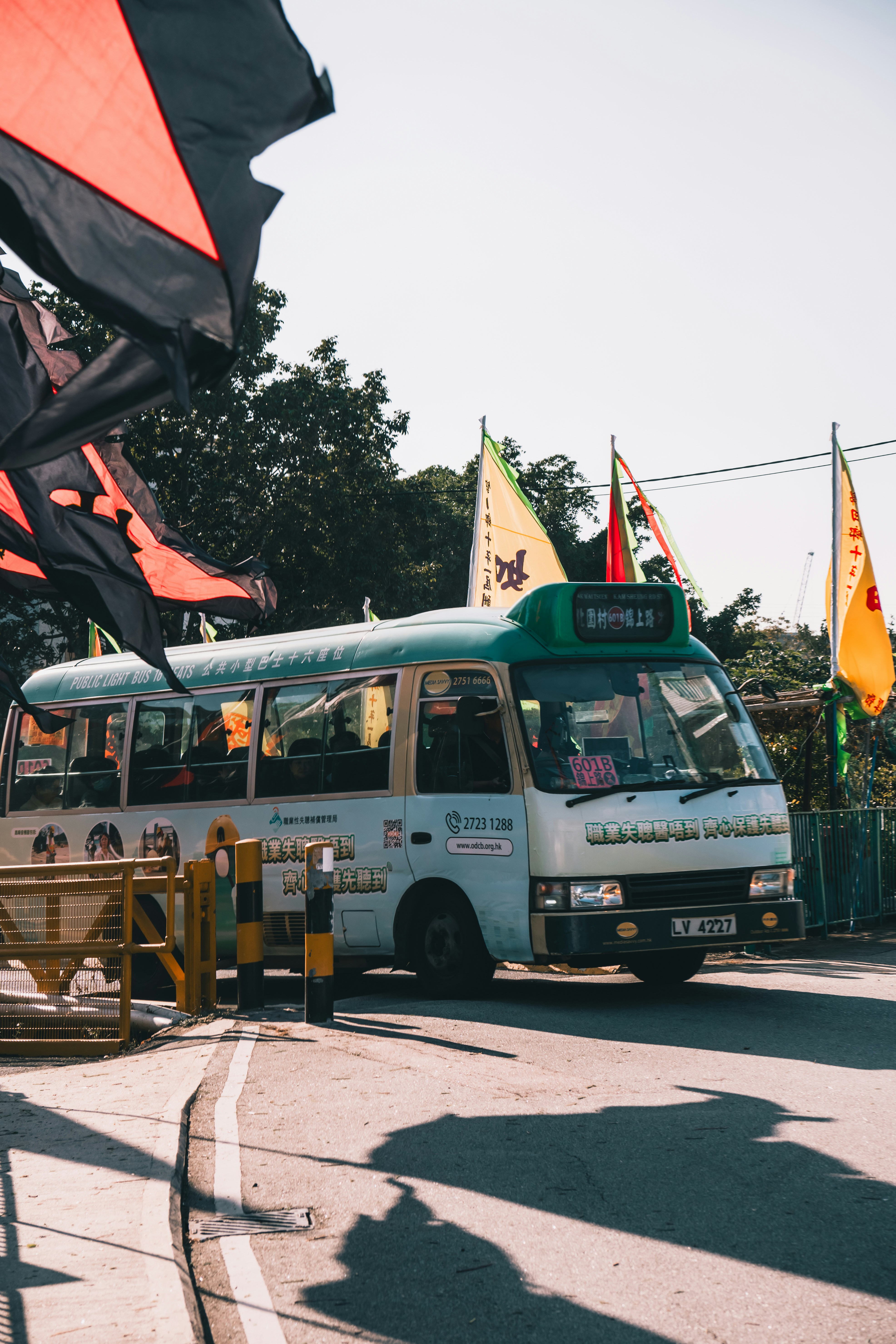 A small bus parked near flags on a sunny day.