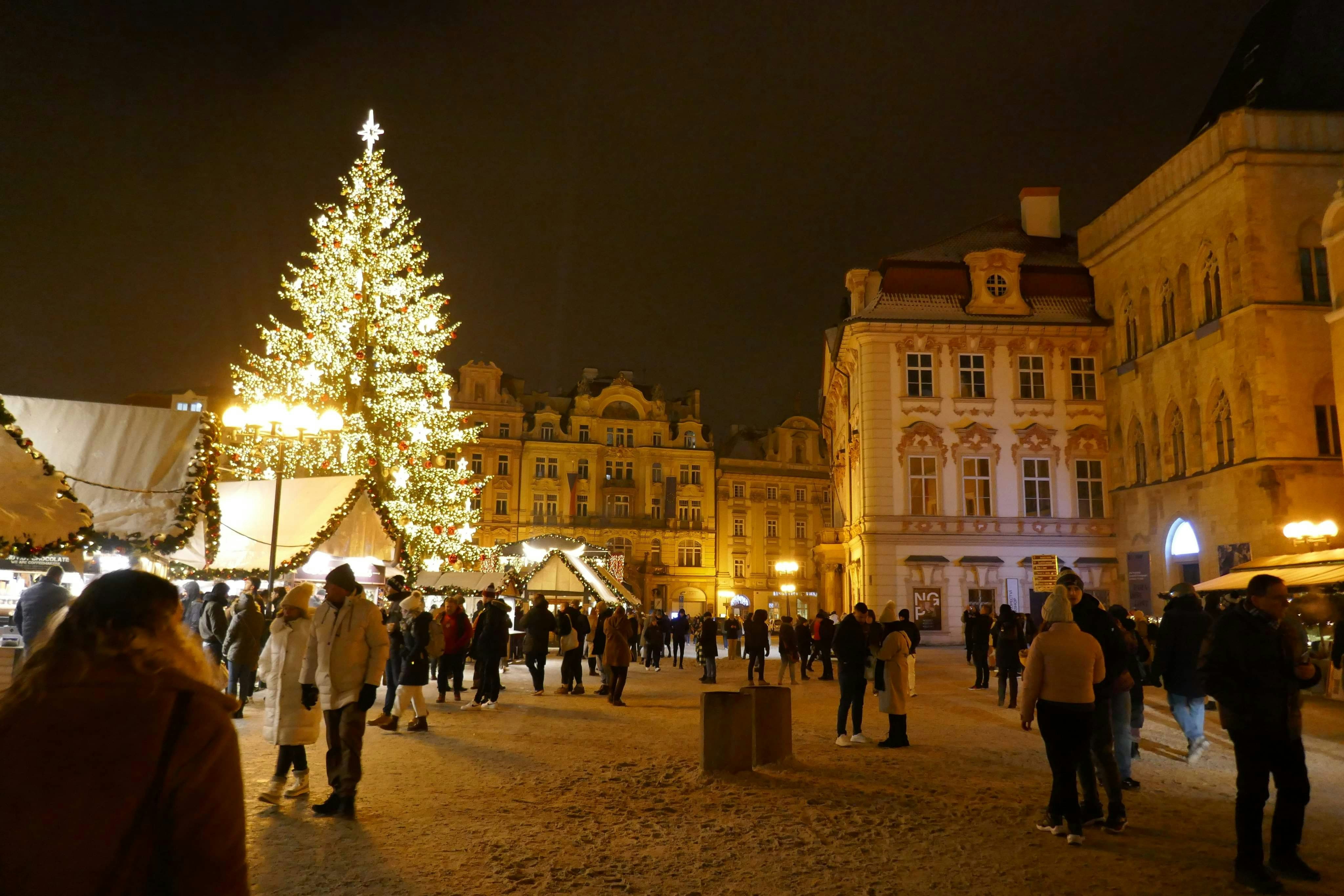 People gather around a christmas tree in a town square.