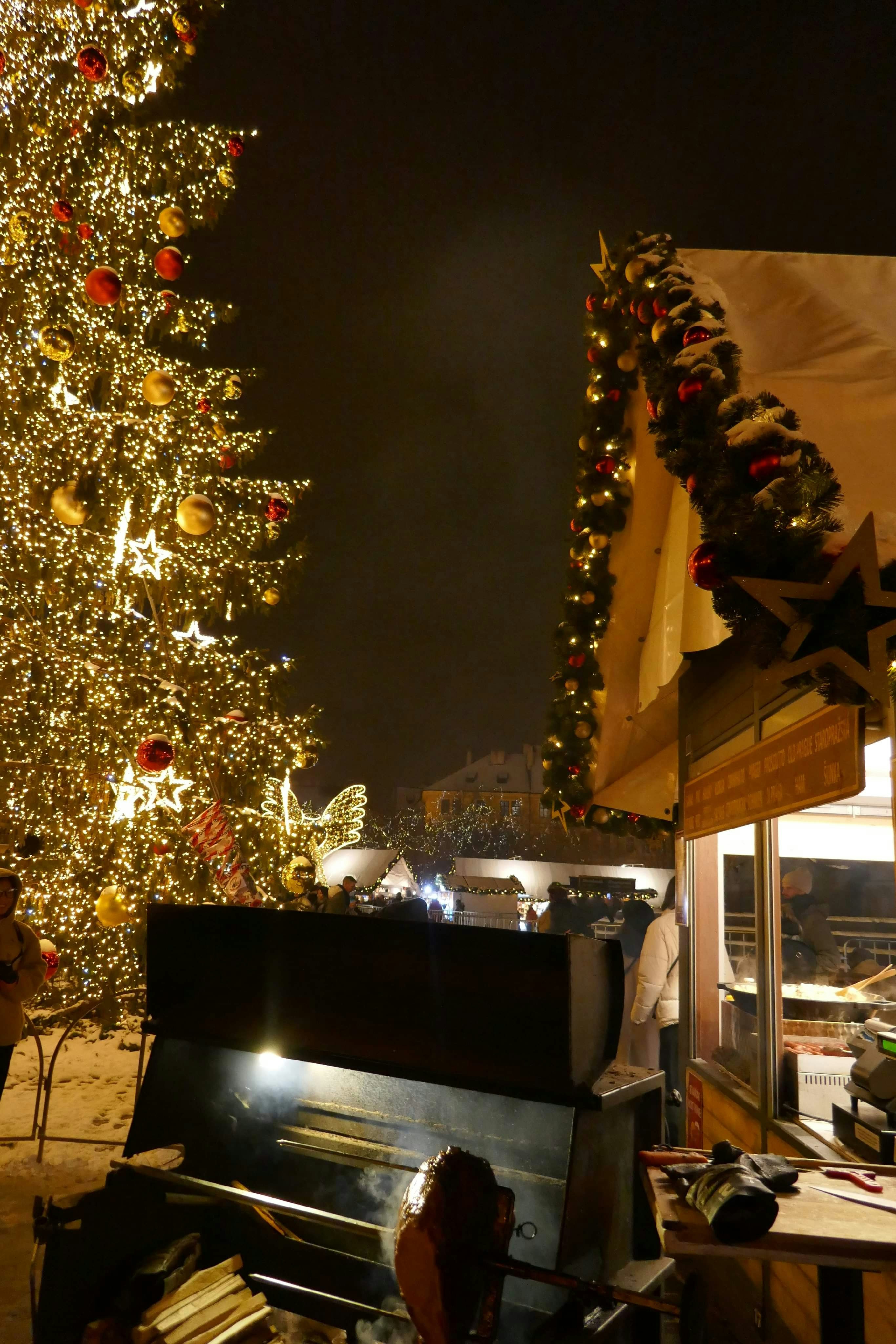 A decorated christmas tree and piano at night.