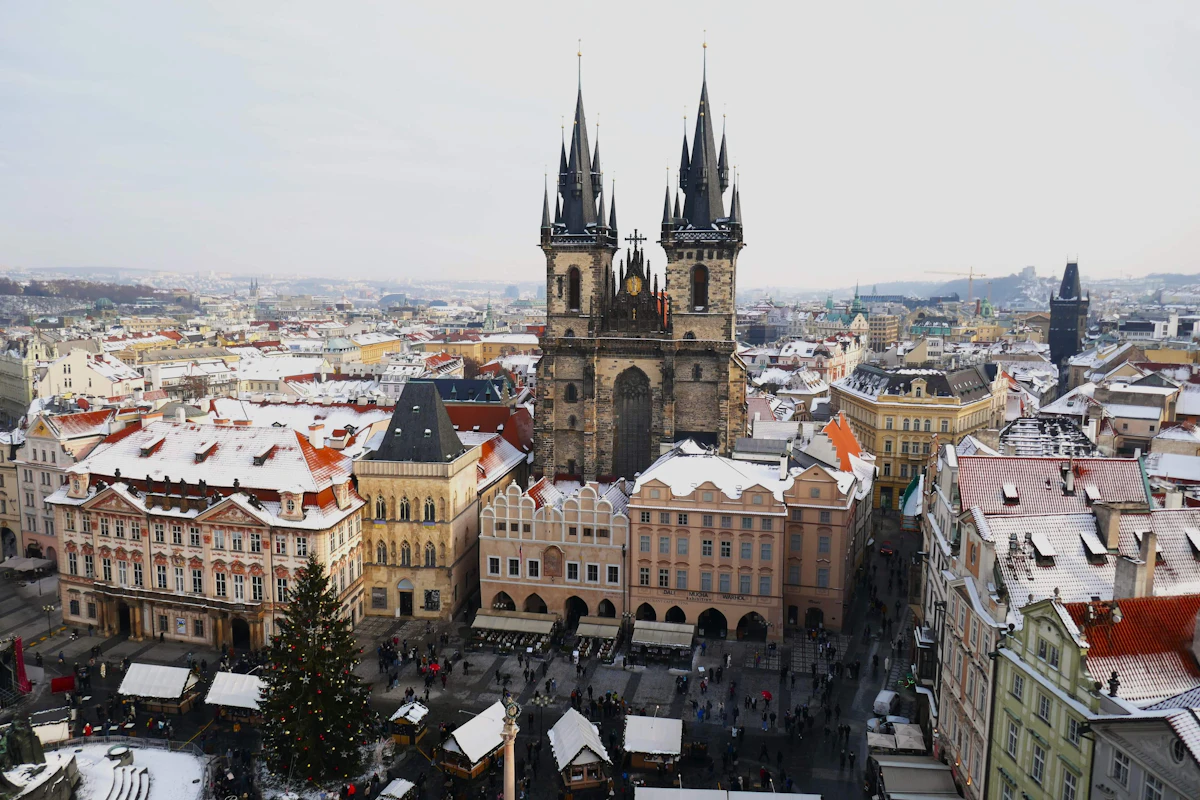 Snow-covered rooftops and gothic church spires above a European old town