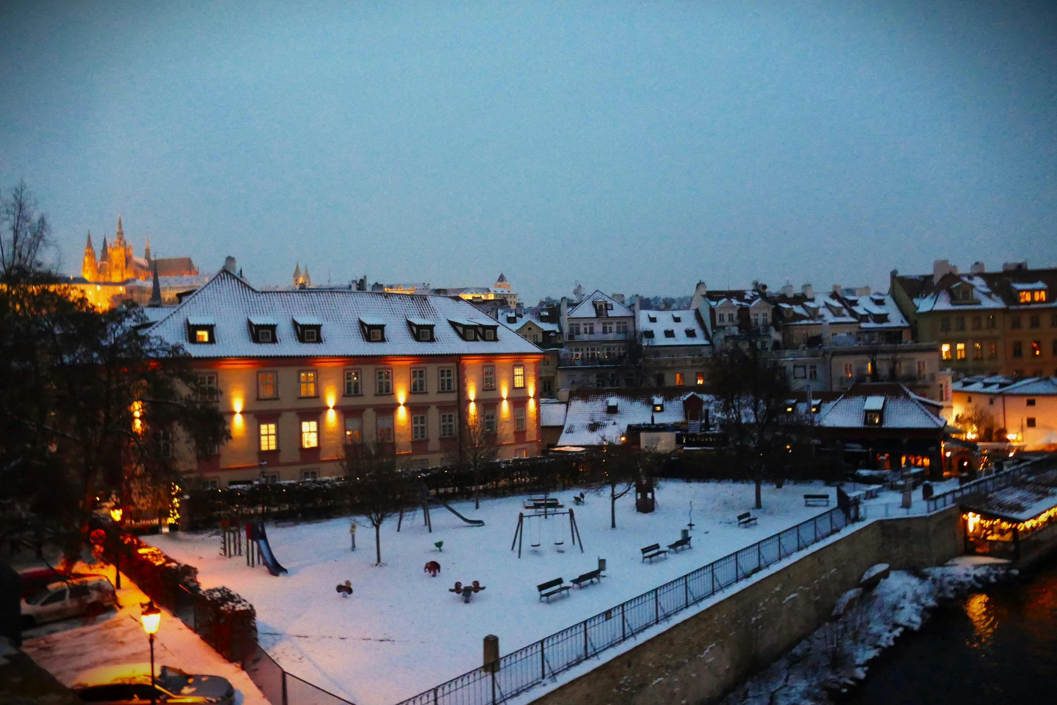 Snow-covered playground in a european city at dusk.