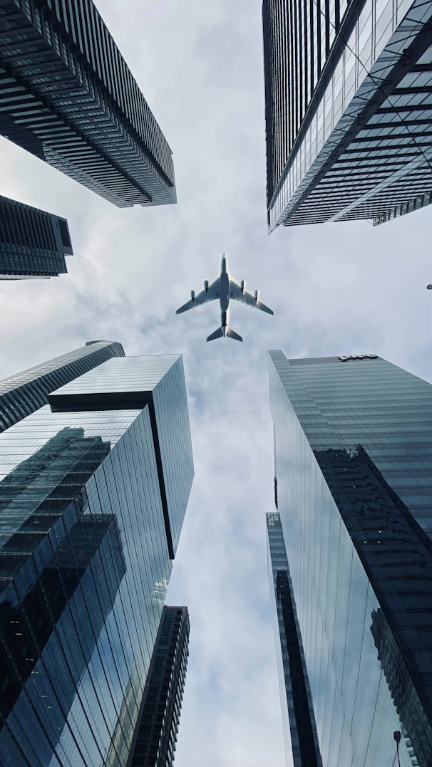 Airplane flying between tall city skyscrapers.