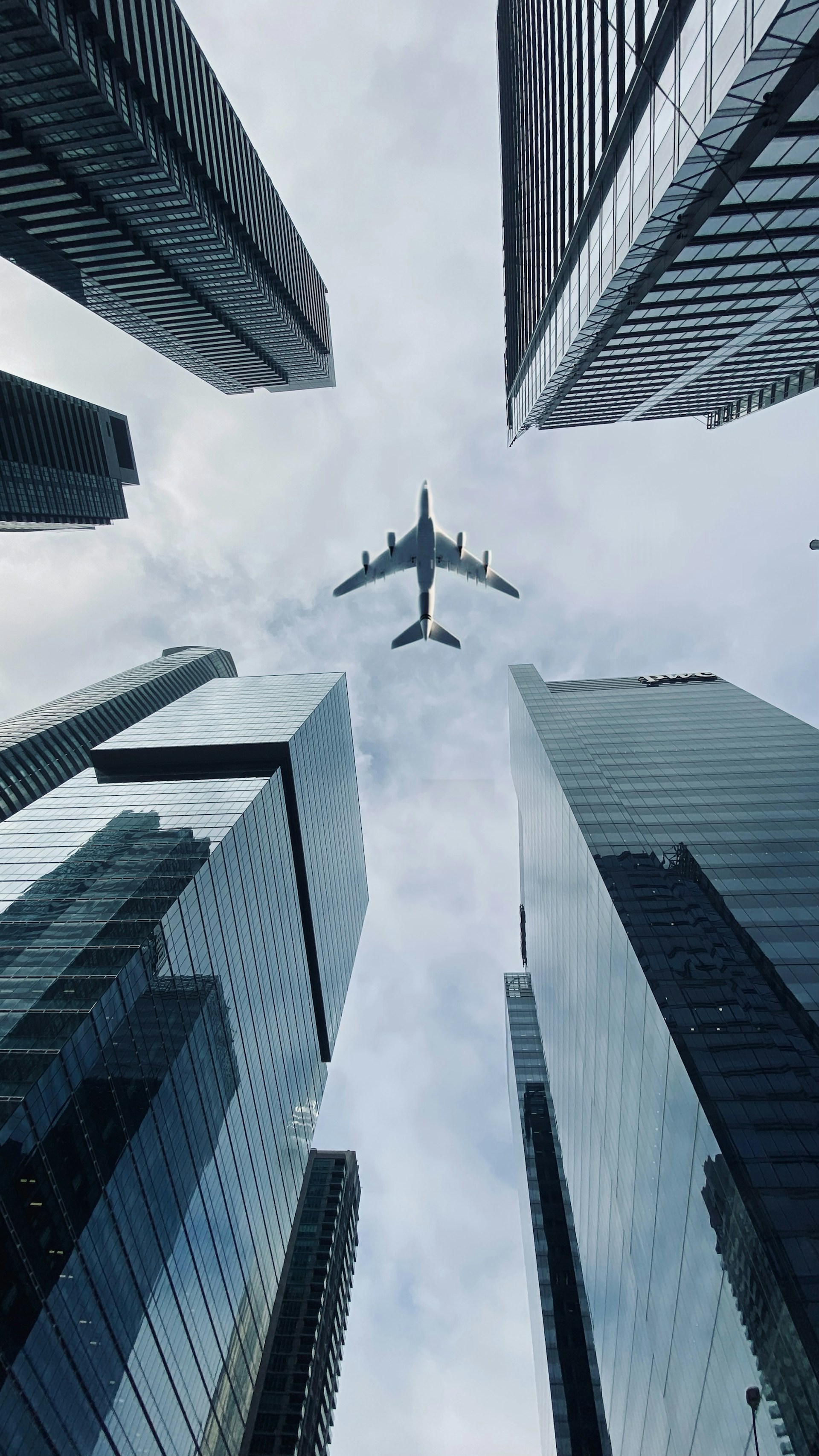 Airplane flying between tall city skyscrapers.