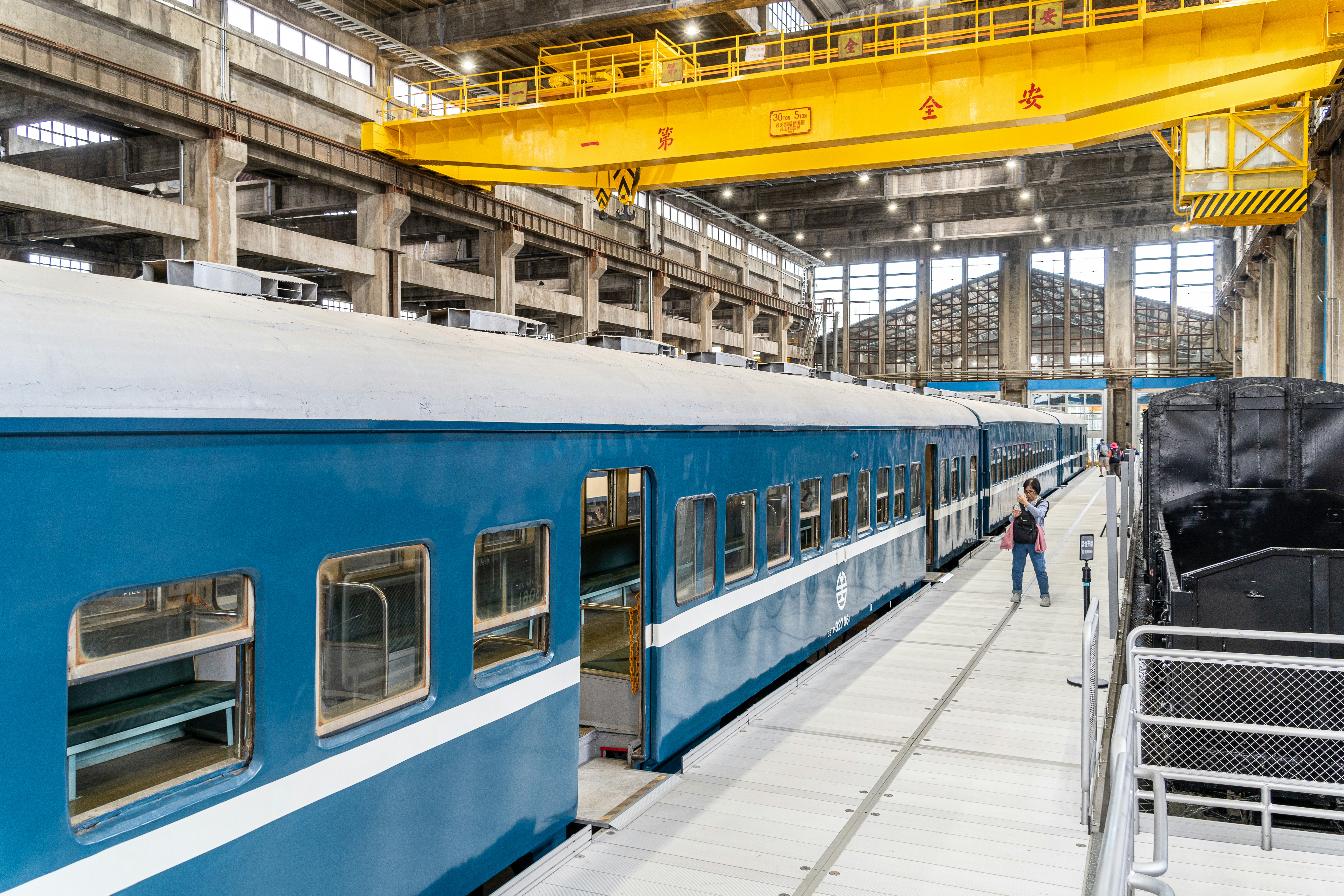 Blue train cars in a large industrial workshop.