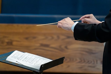 Conductor leading orchestra with baton over sheet music