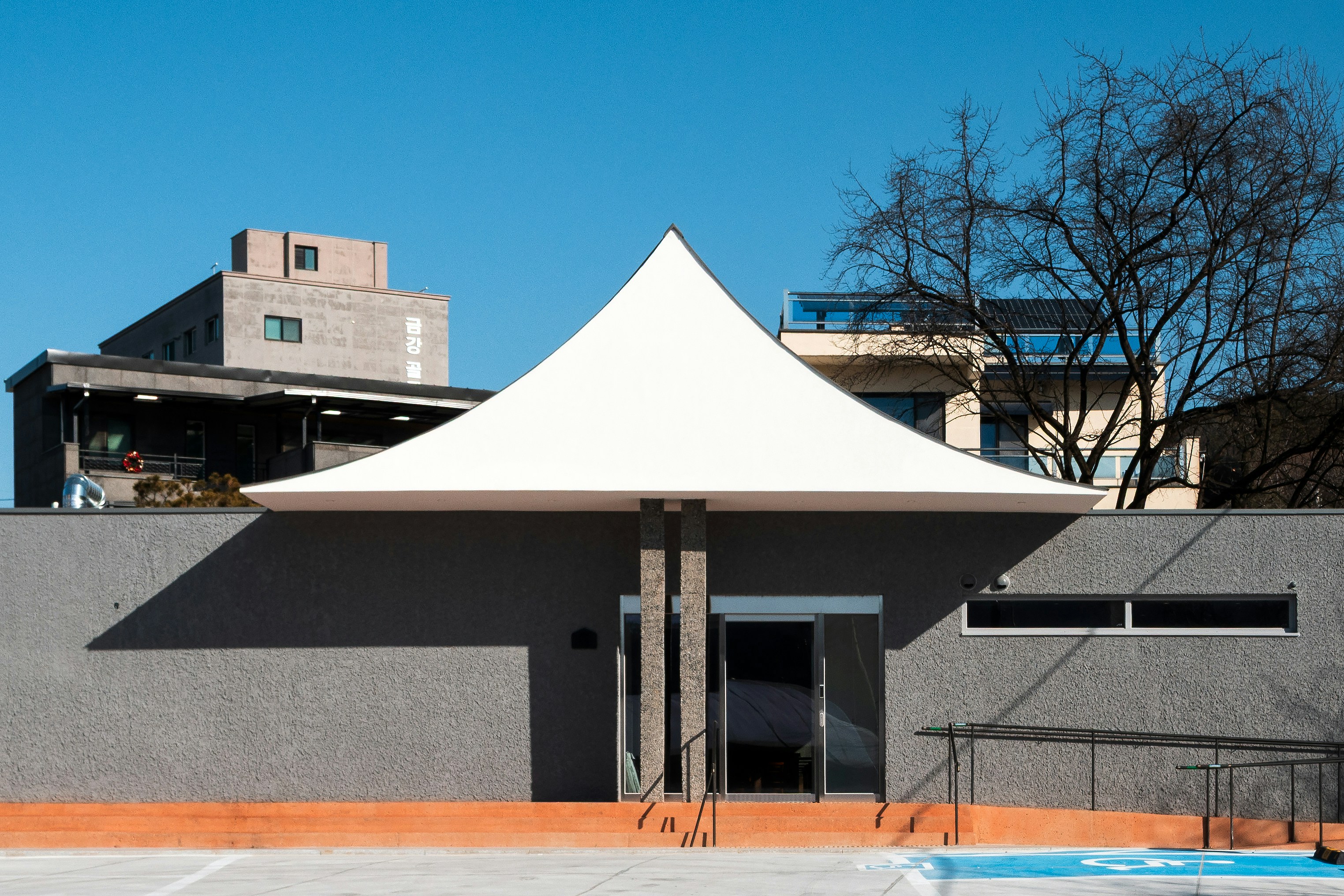 Modern building entrance with white tent-like canopy