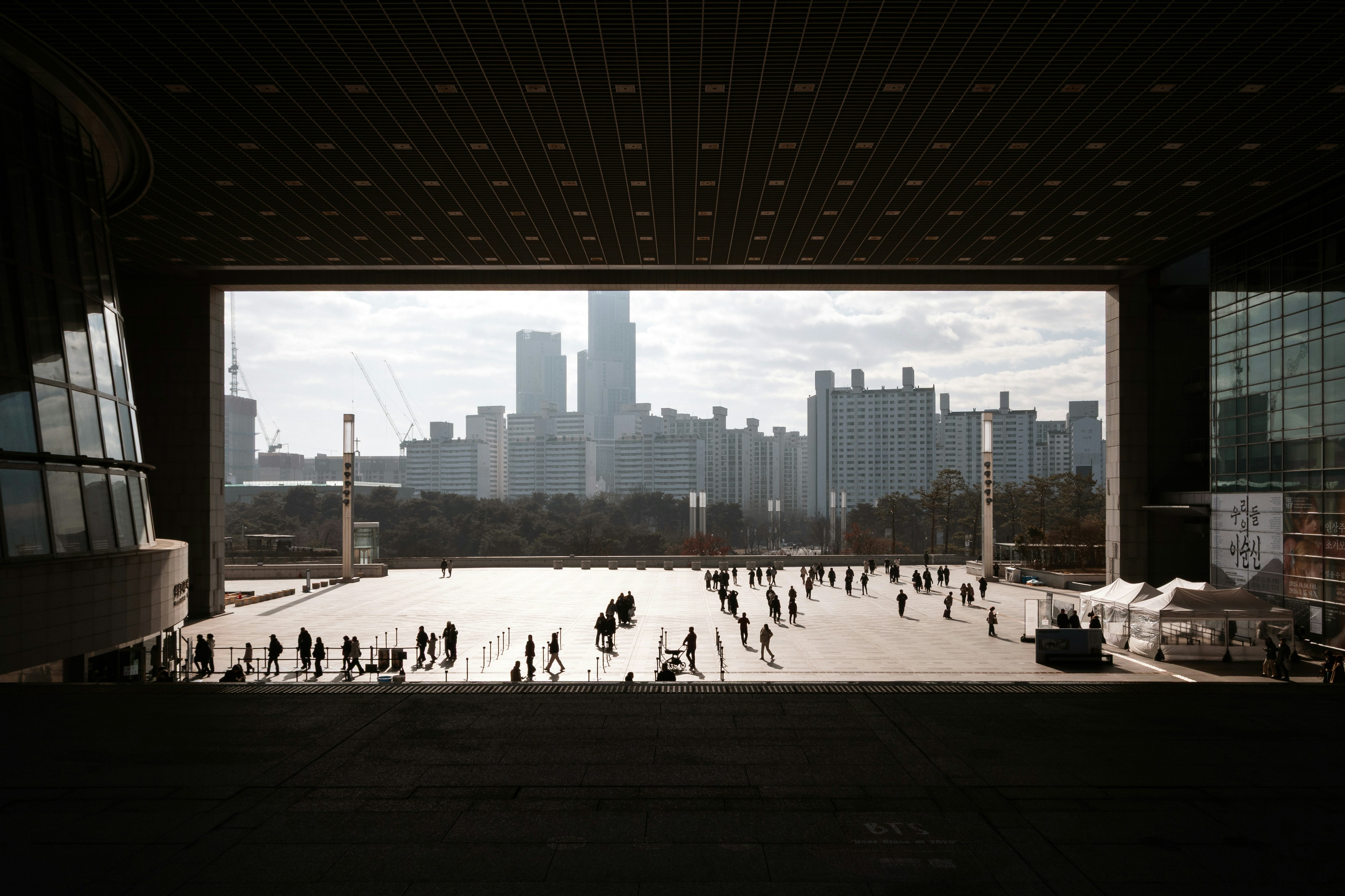 People gather in a large plaza with city buildings beyond.