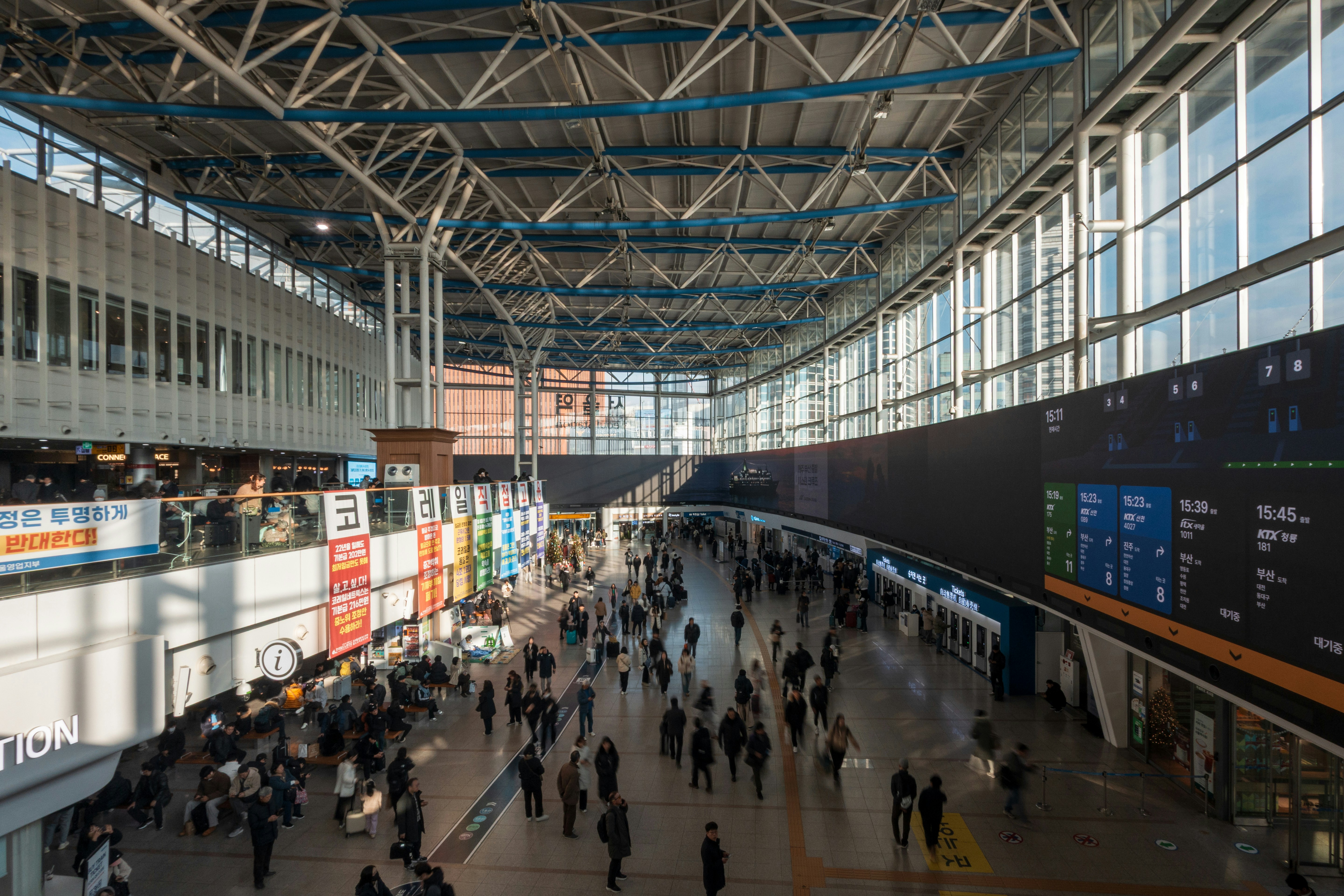 Busy train station concourse with many people walking.