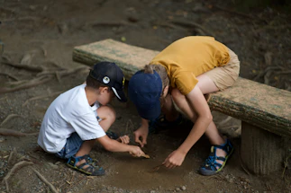 Two children examining something on the ground.